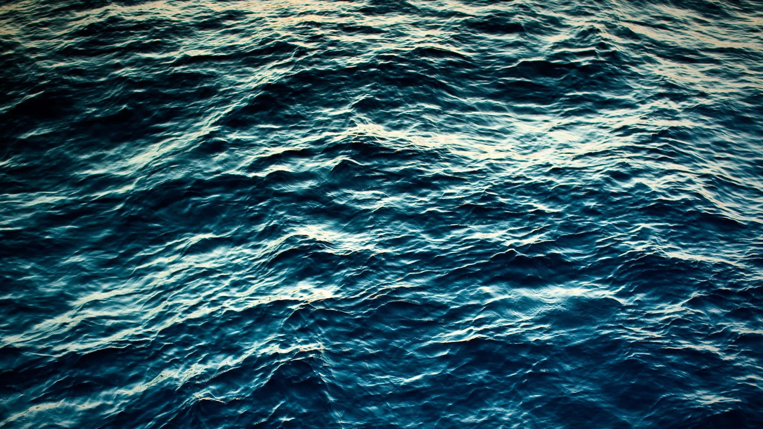 海洋景色之美 壁紙 — 粗糙的海浪在昏暗的光線下泛起漣漪，深藍色和藍綠色調營造出陰鬱的海洋紋理。