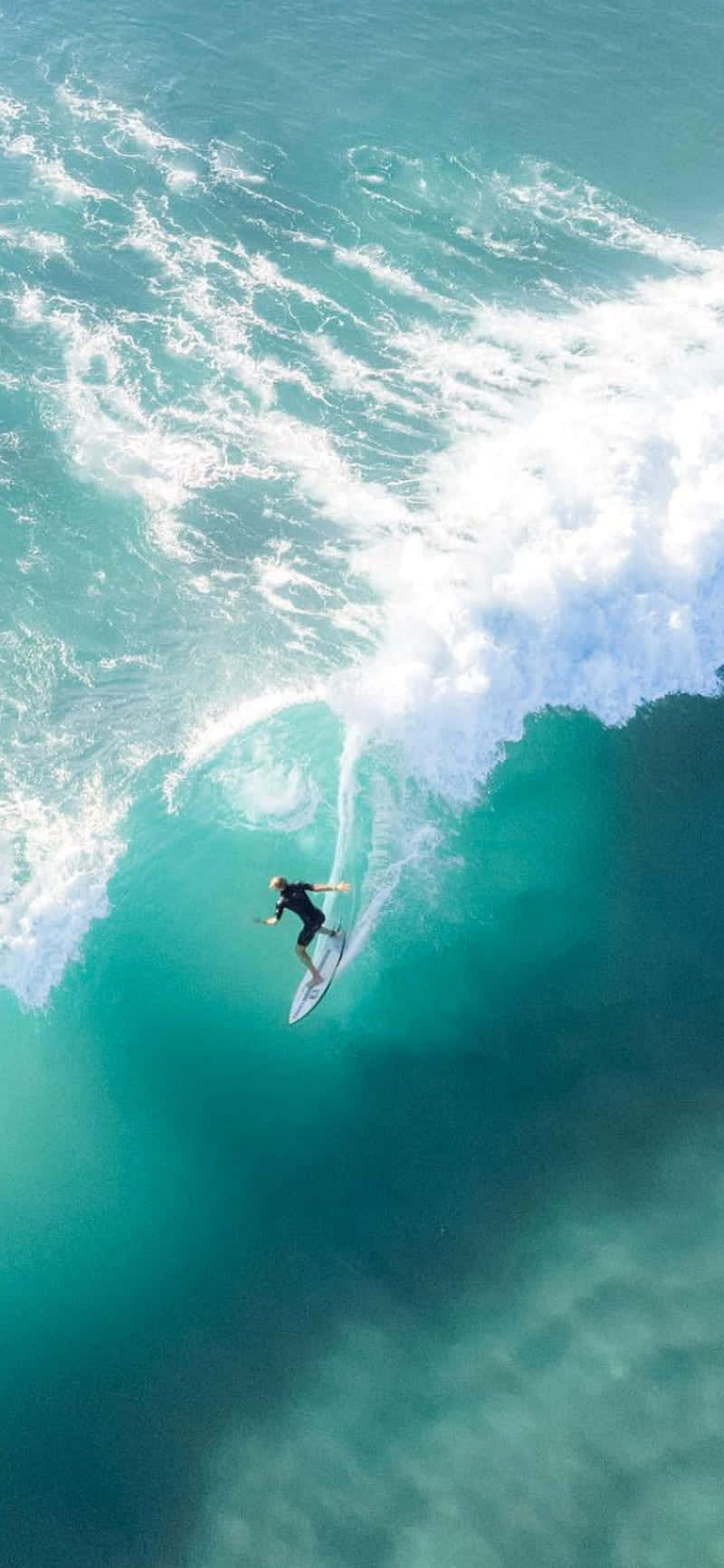 衝浪者從上方滑行在強勁的海浪上。