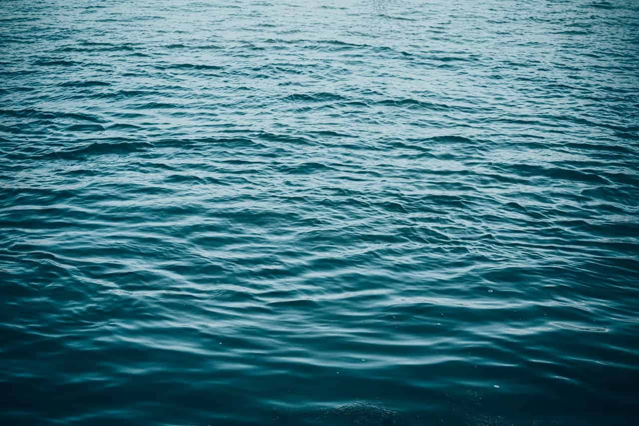 海洋的壯麗景色 壁紙 — 平靜的藍綠色海水近距離特寫，在柔和散射光線下呈現輕微波紋。