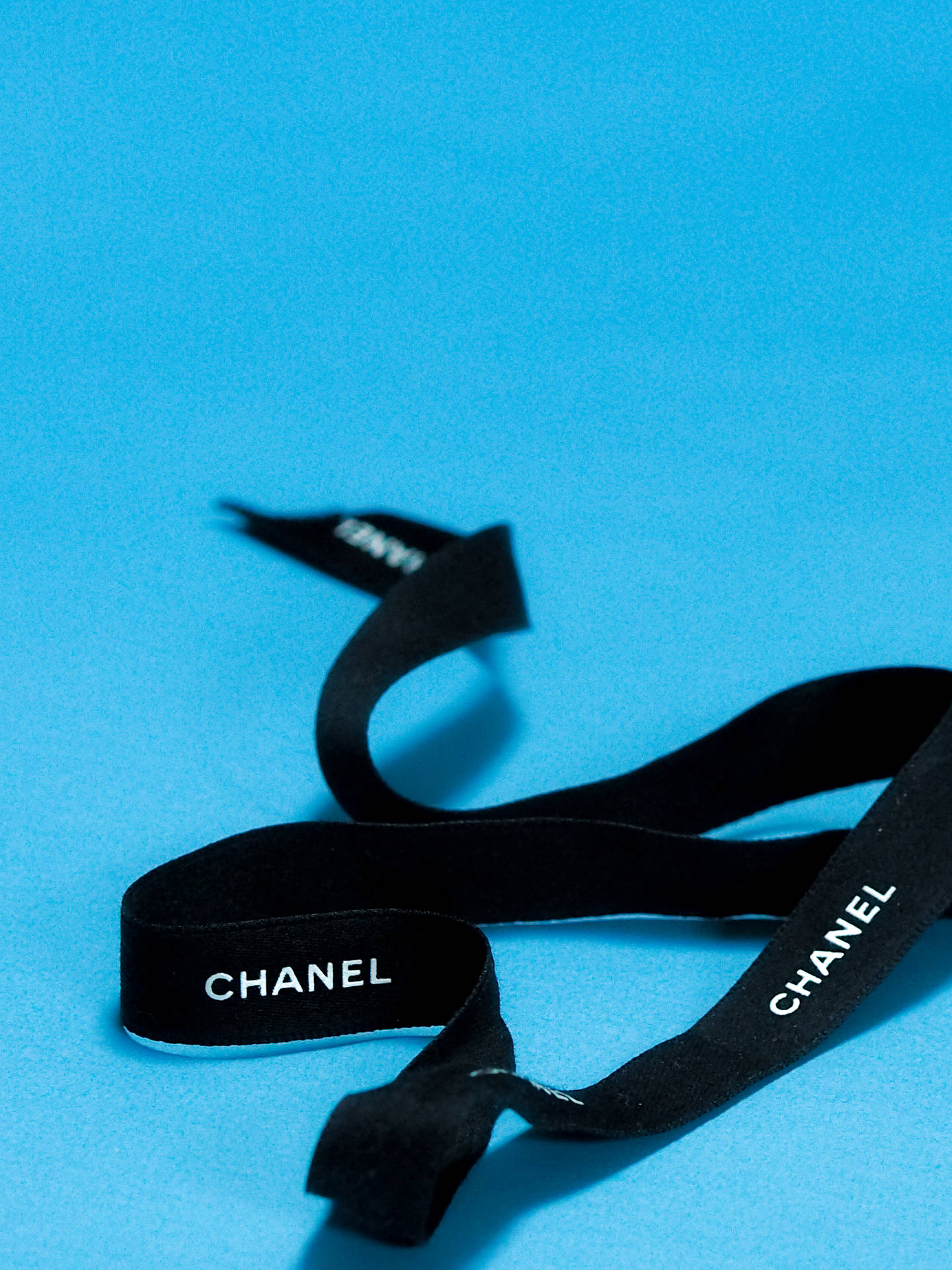 藍色背景上的黑色Chanel絲帶，帶有白色標誌