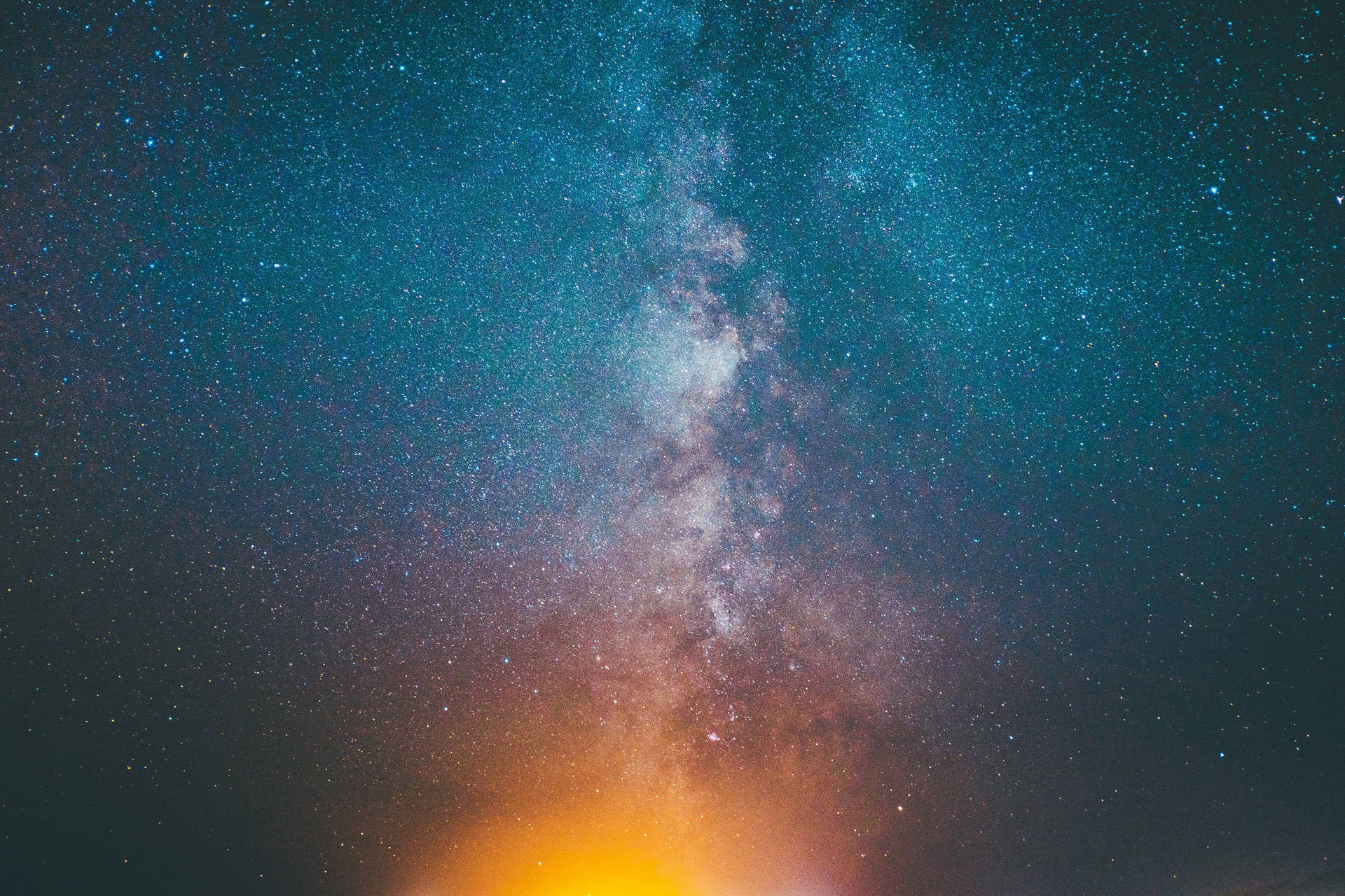 銀河系在繁星點點的夜空中散發著青綠色和橙色的色調。