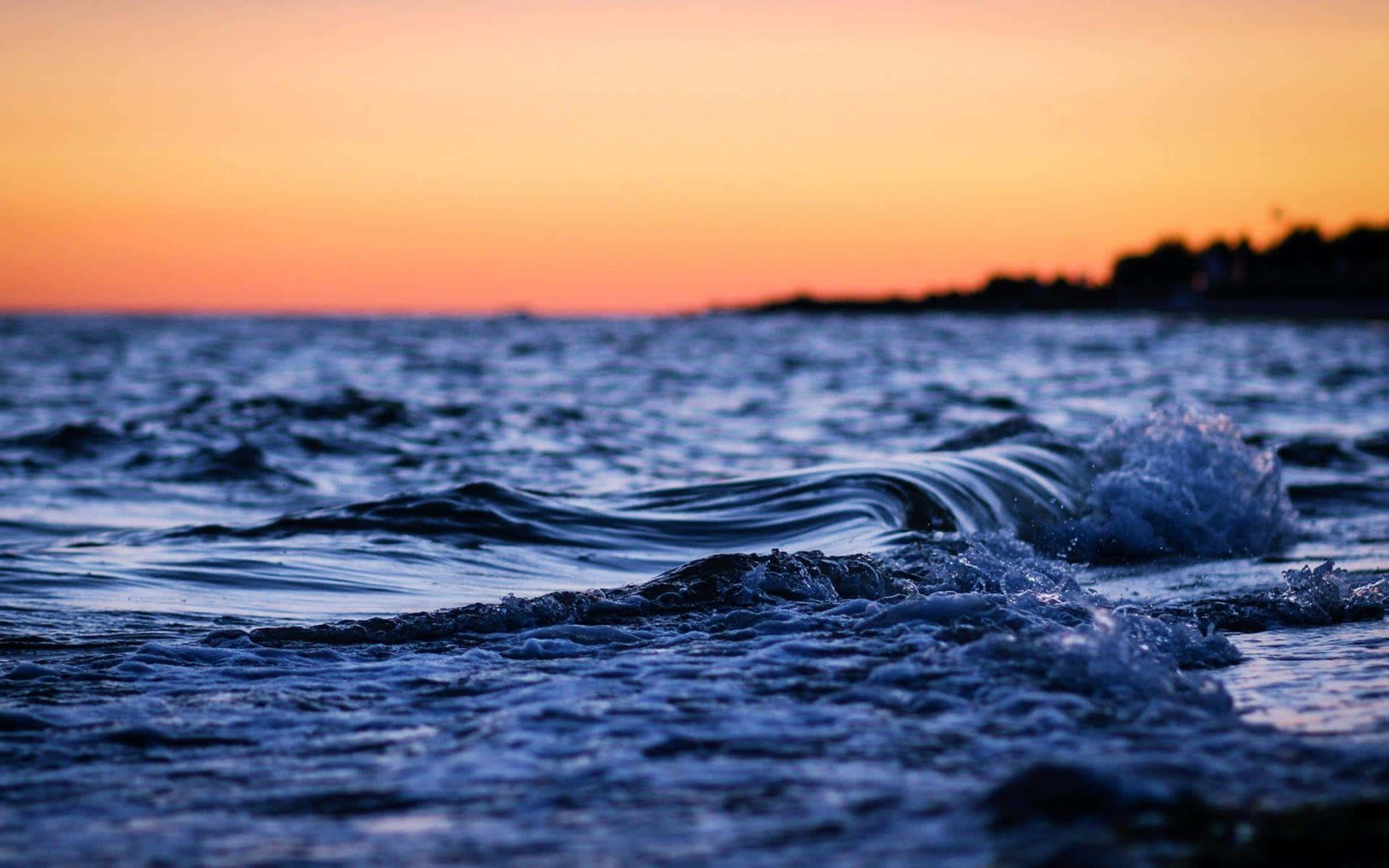 waves 桌布 壁紙 — 海浪在充滿活力的橙色和粉紅色日落天空下拍打海岸。