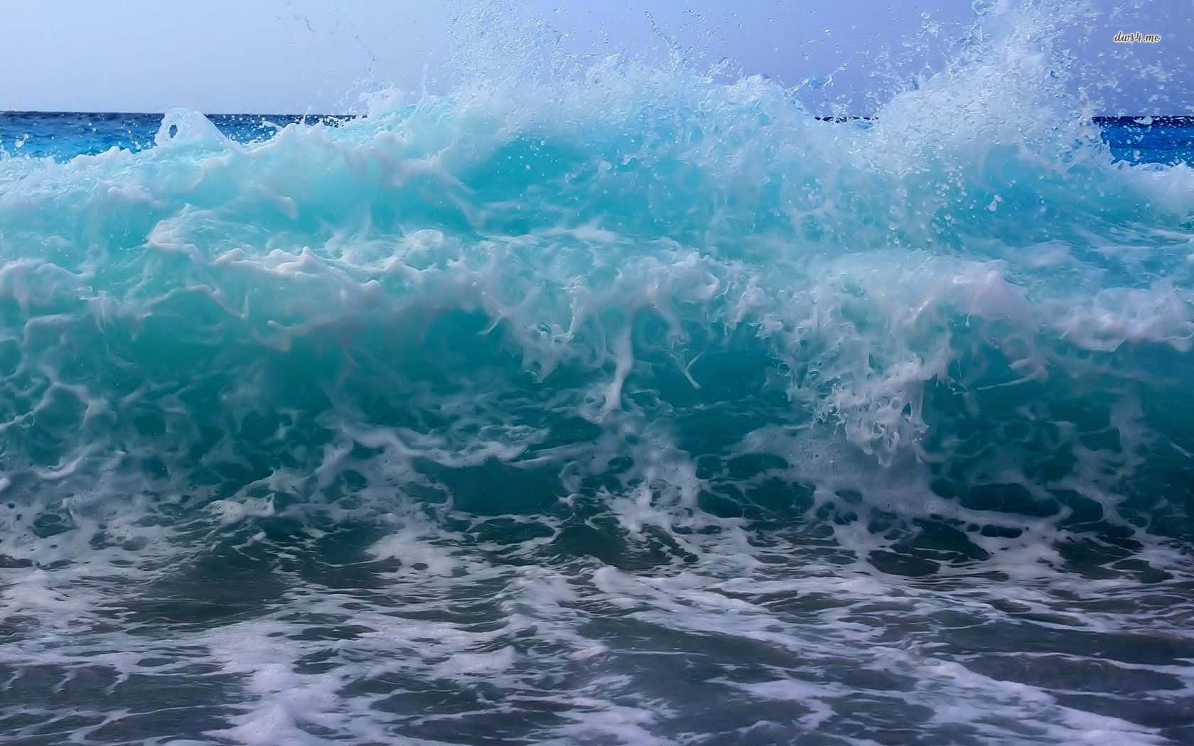 海浪拍岸海灘美學筆電 壁紙 — 在清澈的藍天下，一道強勁的綠松色海浪帶著白色泡沫沖向海岸。