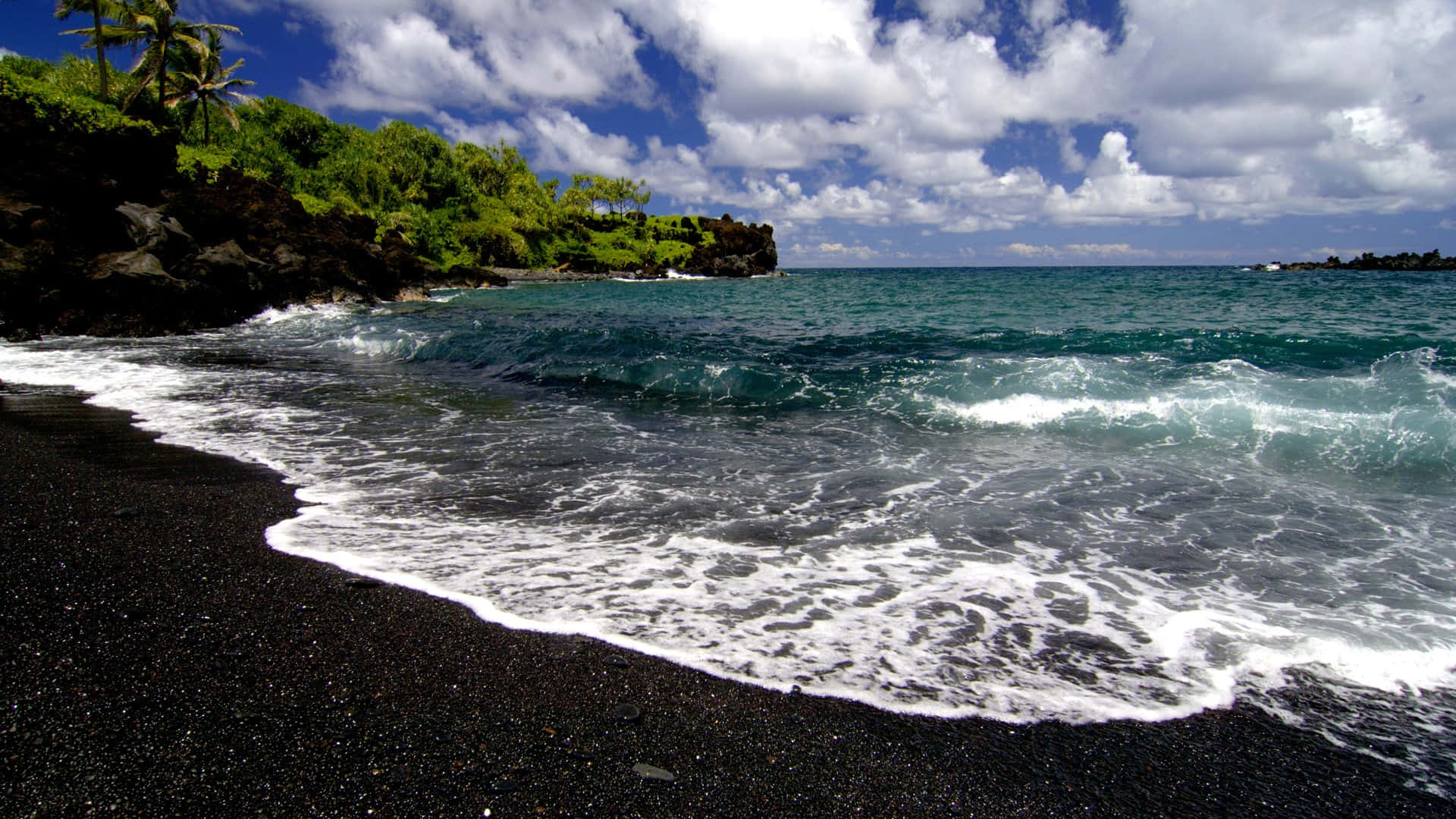 Black Sand Beach 桌布 壁紙 — 海浪拍打黑色火山沙灘，天空湛藍，白雲朵朵。