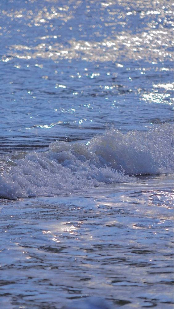 海浪水景照片 壁紙 — 陽光在泡沫般的海浪上舞動，海浪滾滾湧上沙灘，呈現寧靜的海岸景色。
