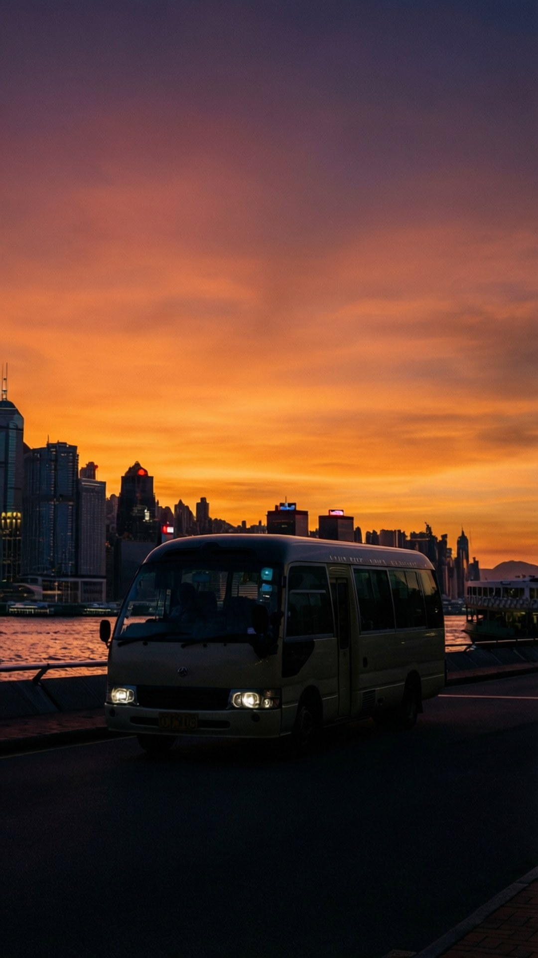 夕陽下，客貨車沿城市海濱行駛，天空呈橙色。