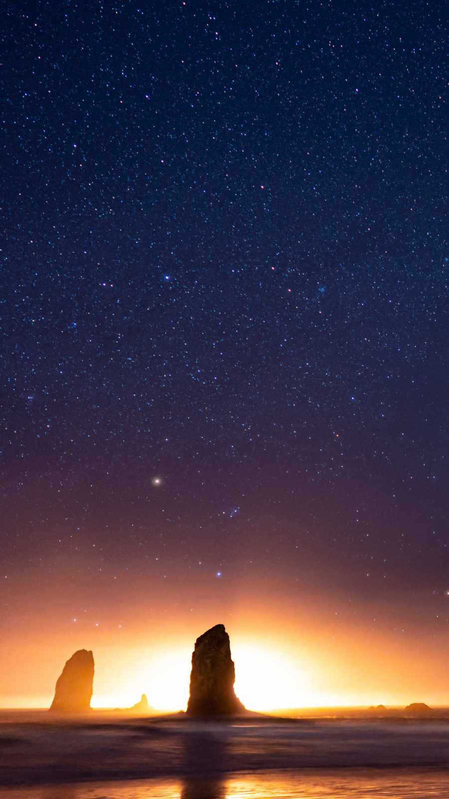 剪影般的海蝕柱在星空黃昏天空下，帶有發光的地平線。
