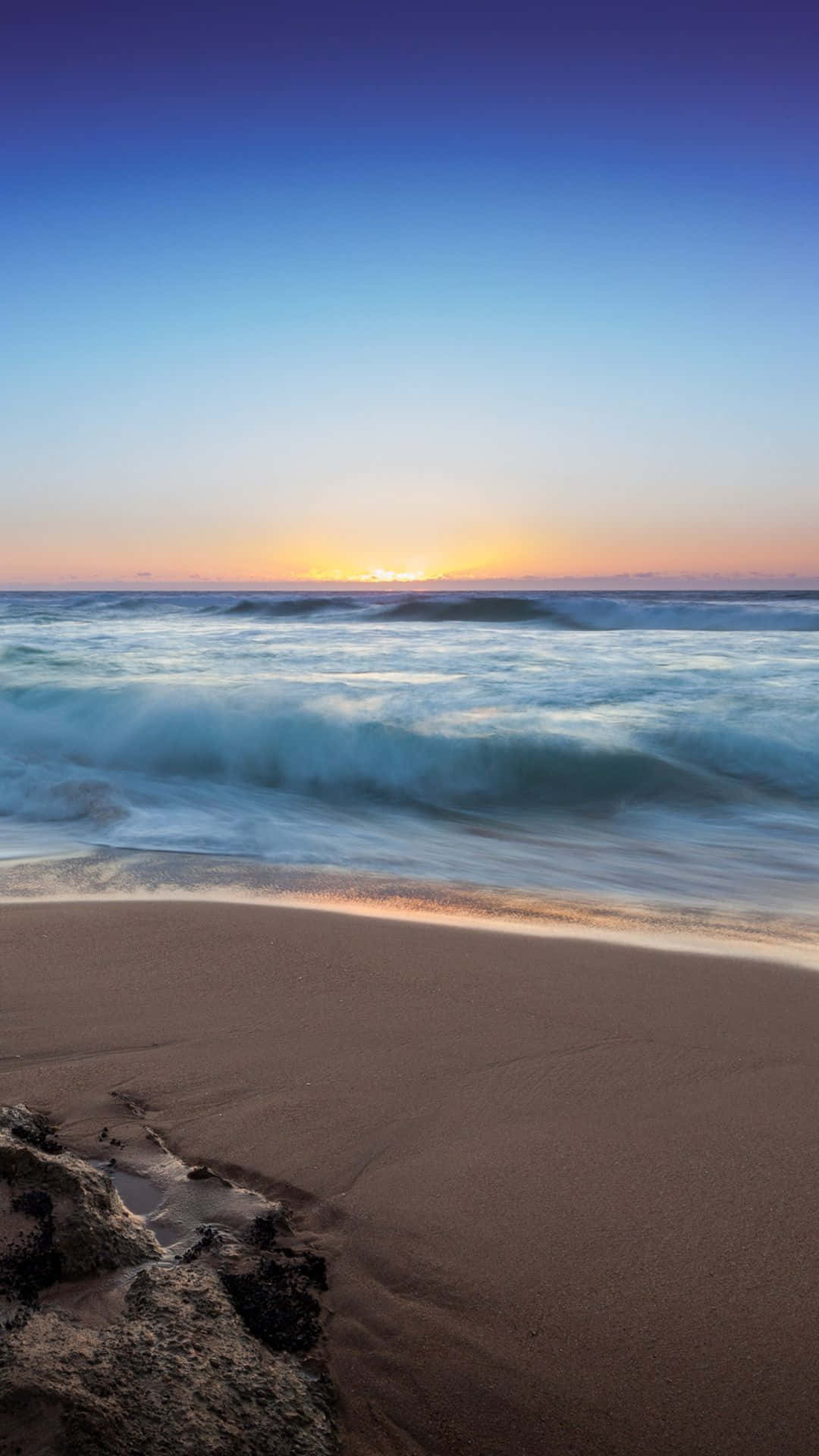 夕陽映照海洋，海浪拍打沙灘