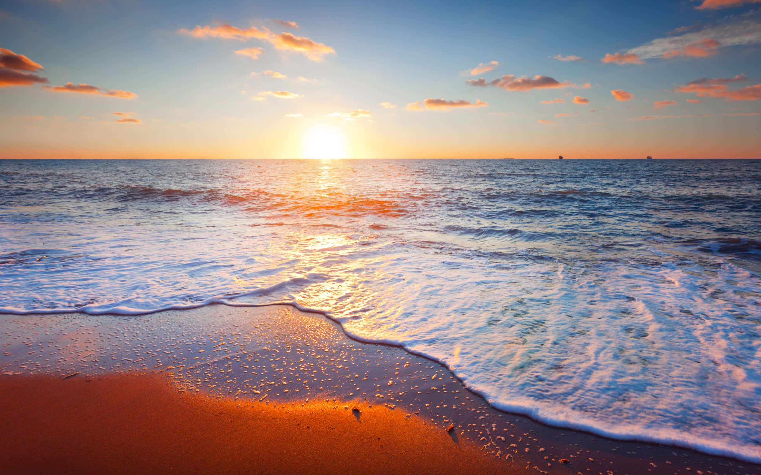 海灘旁的放鬆天堂，適合度假 壁紙 — 夕陽將海洋和沙灘染成溫暖的金色和橙色，溫柔的海浪拍打著岸邊。