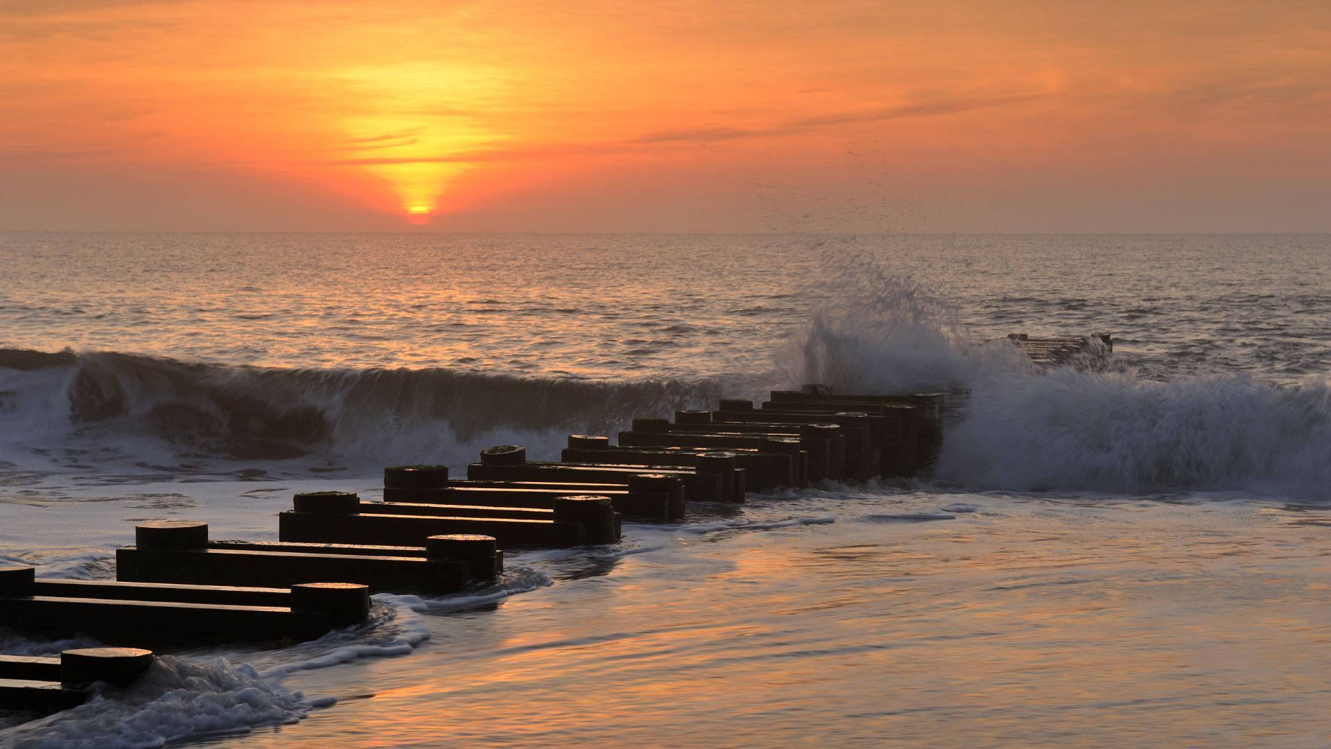 海洋上的夕陽，海浪拍打防波堤塊