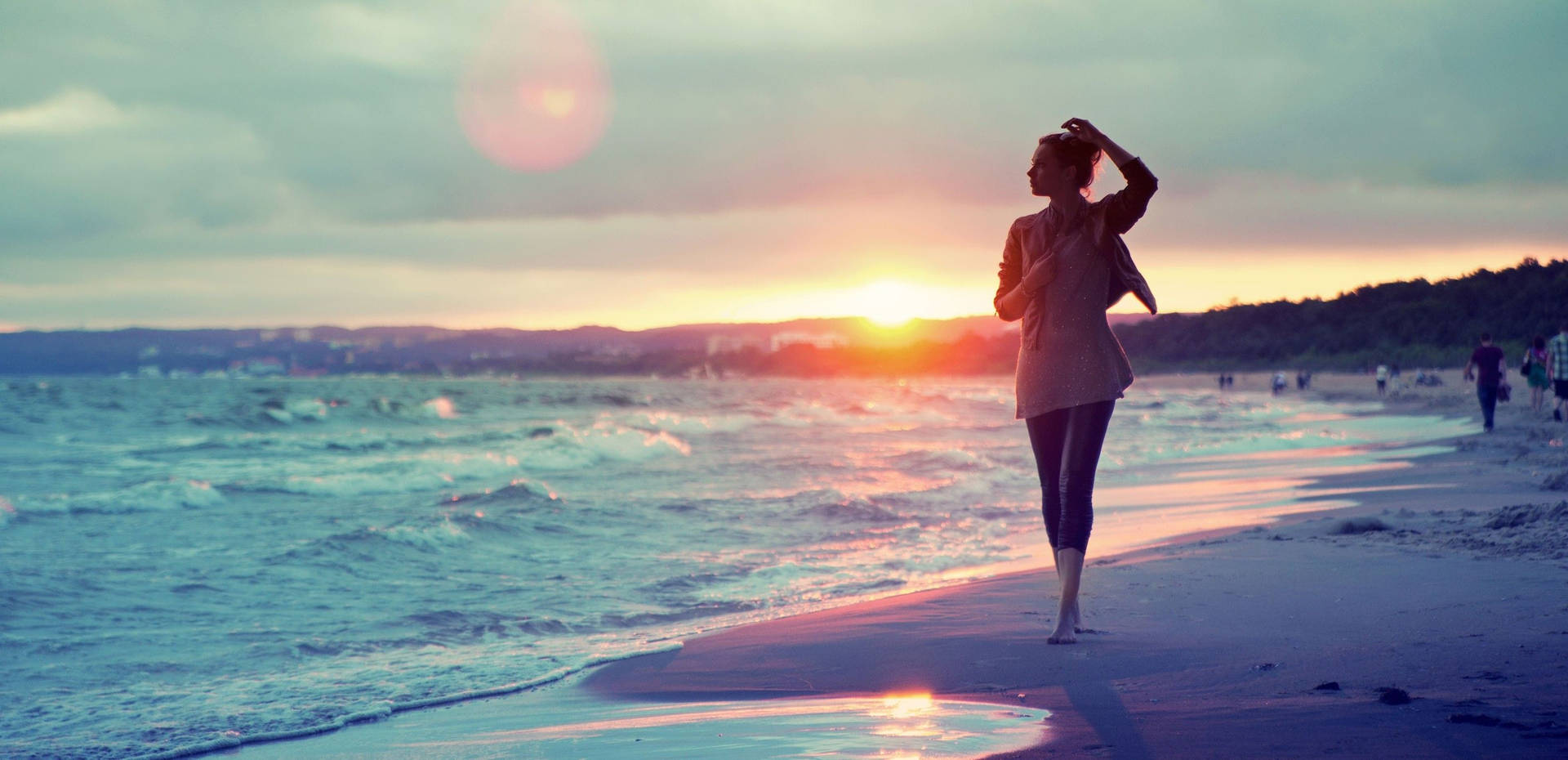 女子在日落時分在海灘上行走，伴隨著海浪和溫暖的天空