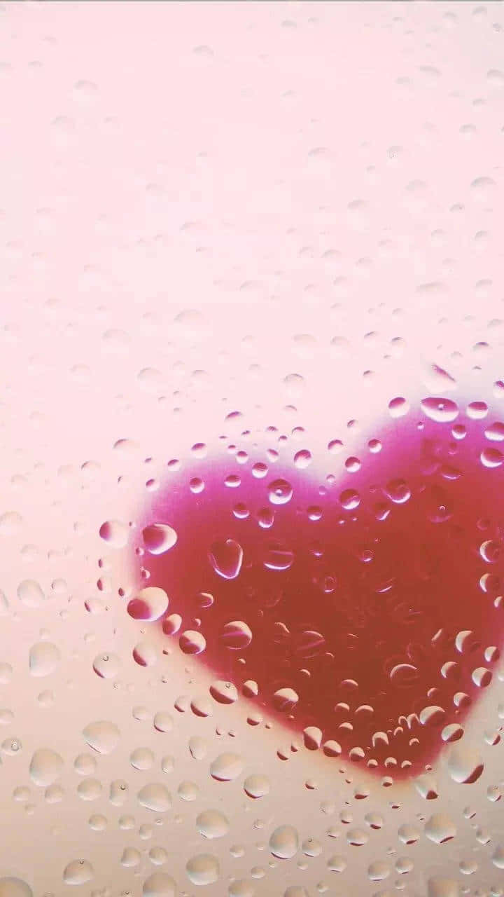 透過雨水浸濕的玻璃看到粉紅色心臟和水滴。