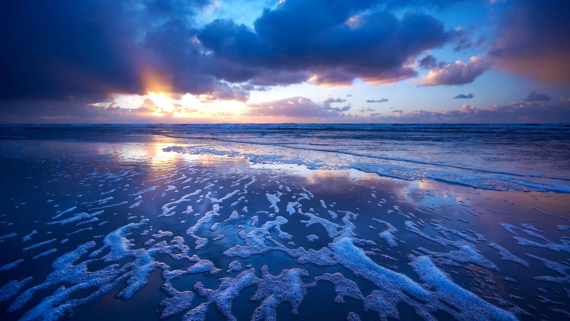 海洋上的夕陽與濕沙上的泡沫波浪