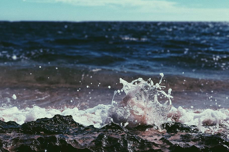 海洋波浪衝擊深色岩石，白色泡沫飛濺