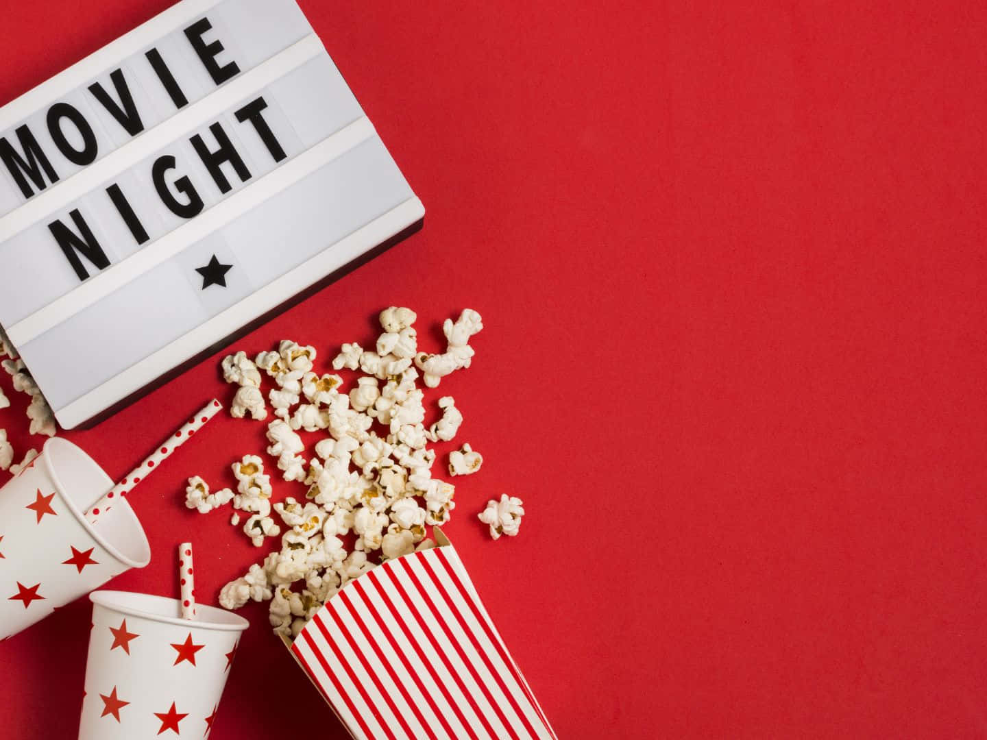 海灘清晨的清新景致 壁紙 — 紅色背景上有一個發光箱，上面寫著「MOVIE NIGHT」，旁邊有灑出的爆谷和星星圖案的杯子。