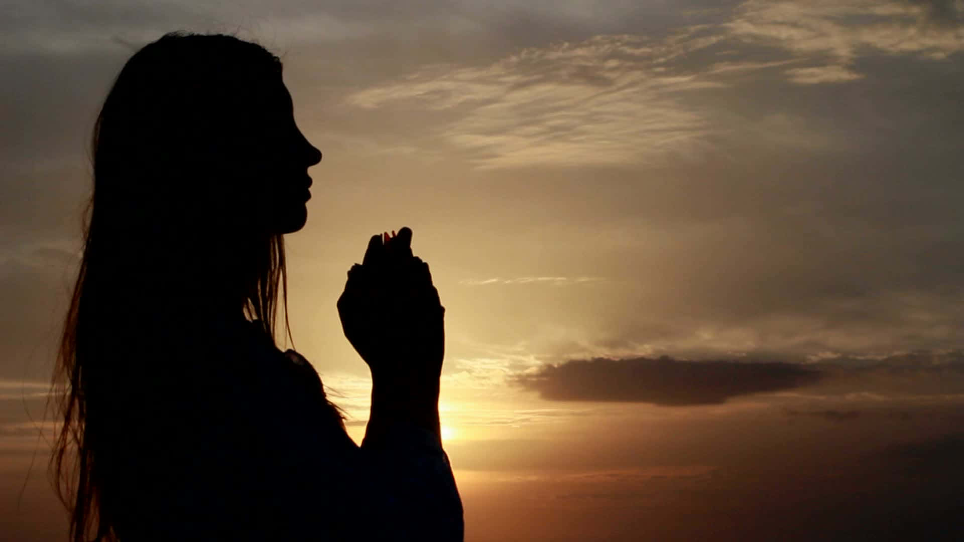 日落時祈禱的女性剪影