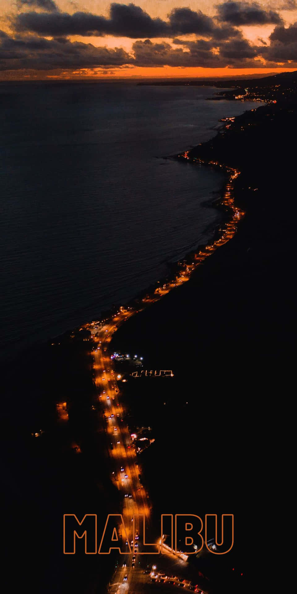 馬里布海邊在黃昏時分，沿著海岸有發光燈光的沿海道路。