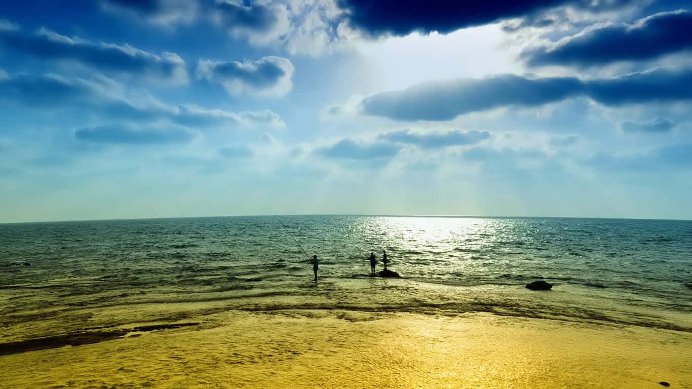 海灘陰天 1366x768 顯示器背景 壁紙 — 兩個剪影人物站在海邊，陽光穿過戲劇性的雲層，灑在金色的沙灘上。
