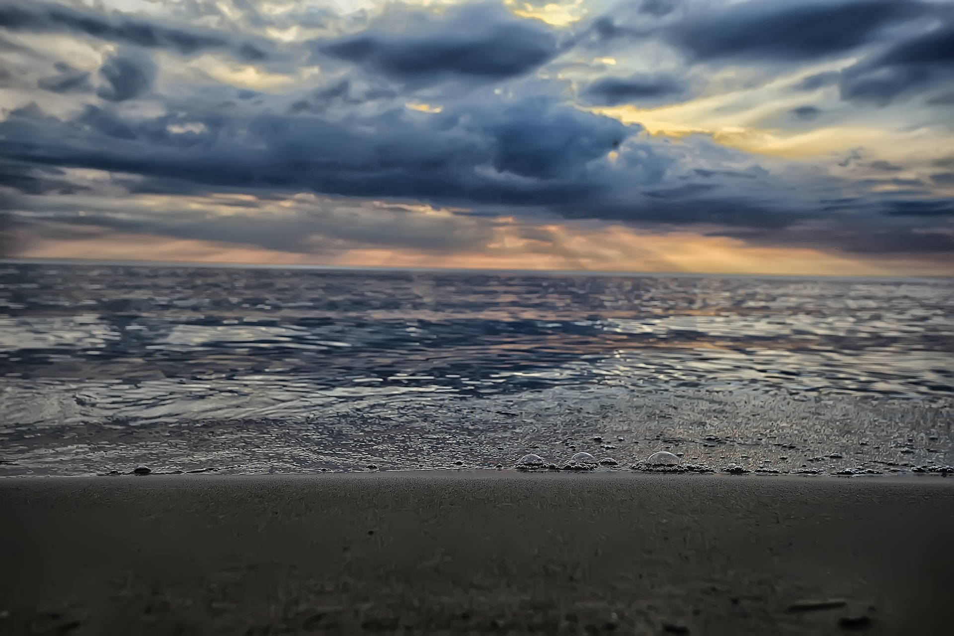 海洋上的日落，帶有戲劇性的雲和前景的濕沙