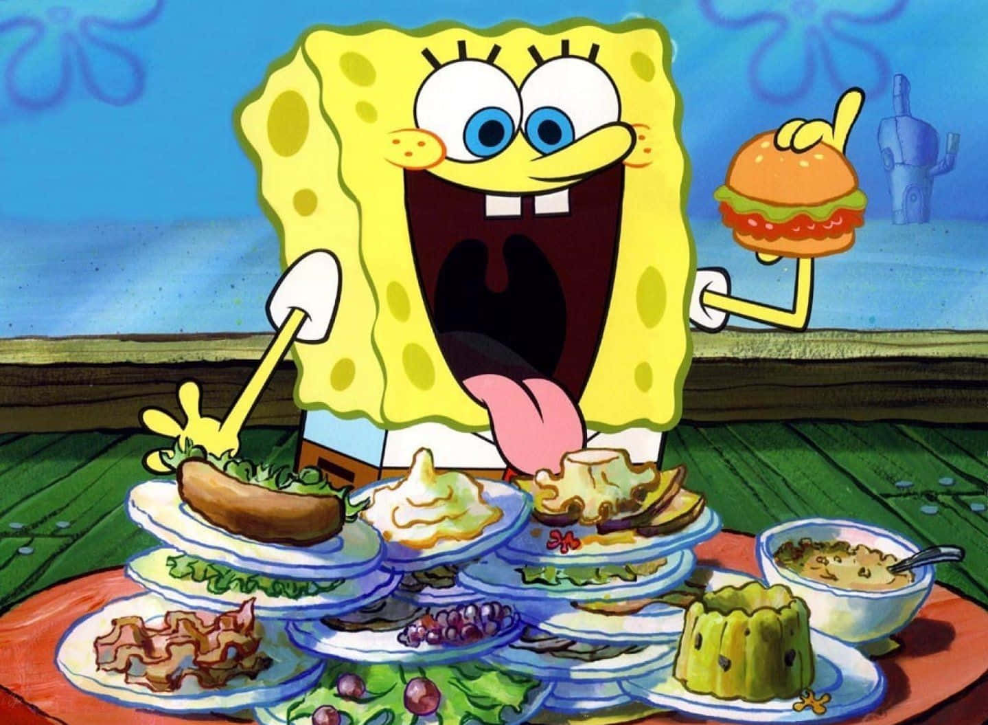 Krabby Patty 桌布 壁紙 — 海綿寶寶開心咁拎住一個漢堡包，周圍係木枱上豐富嘅食物。