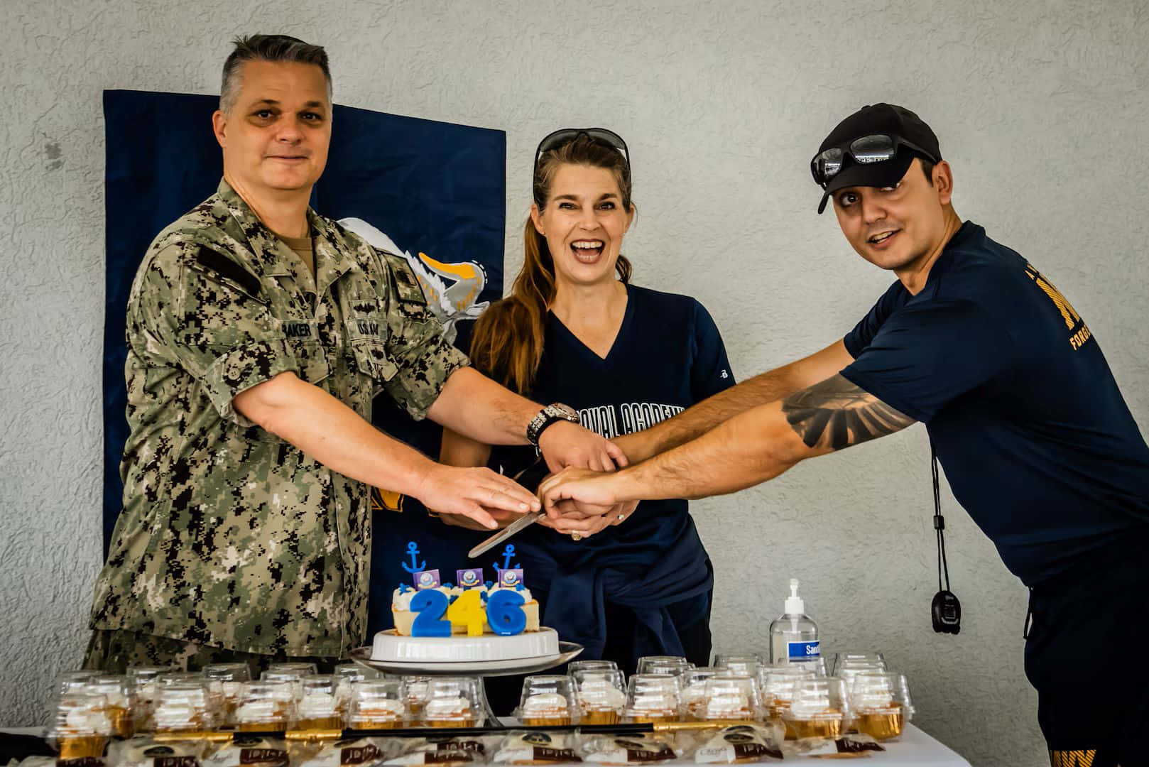 海軍生日慶祝切蛋糕 壁紙 — 三名微笑的海軍人員在喜慶聚會中愉快地切開帶有「216」裝飾的慶祝蛋糕。