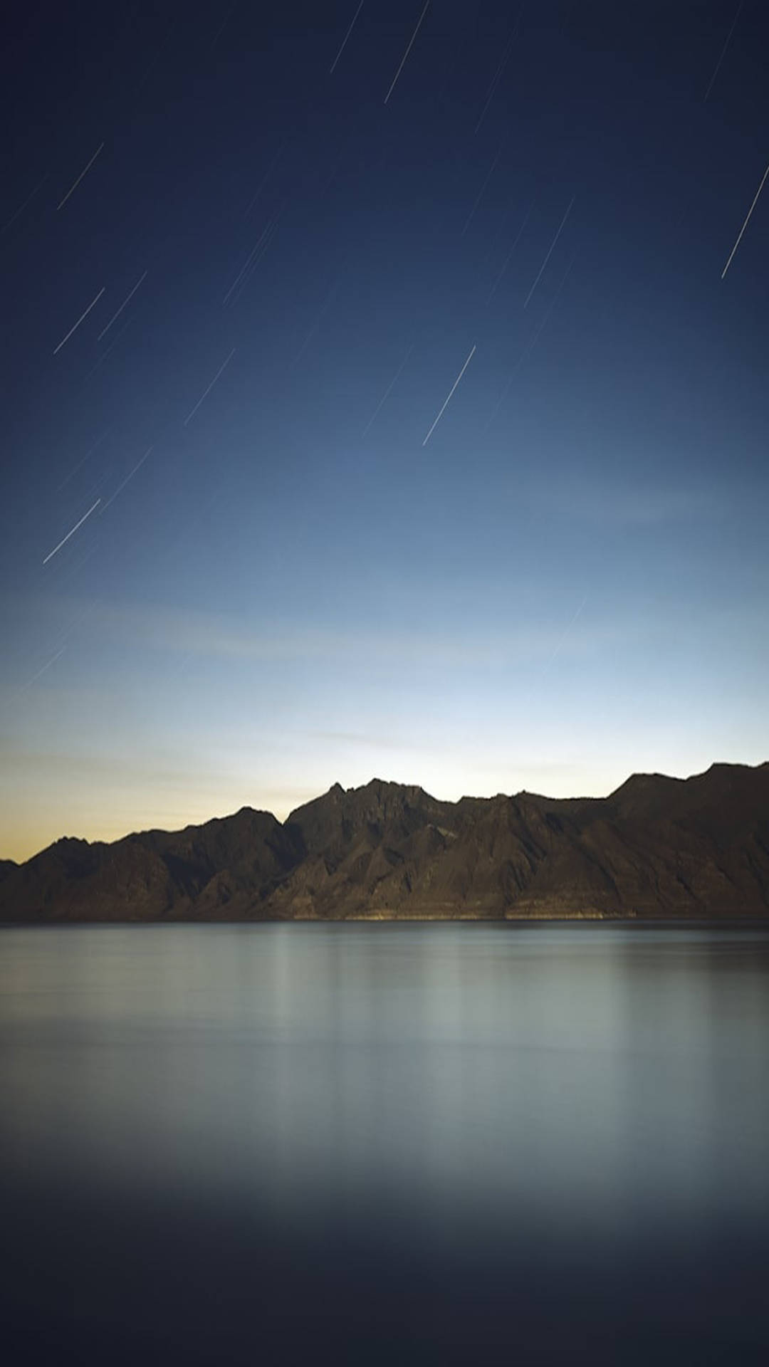 夜晚山巒和水面上的星軌
