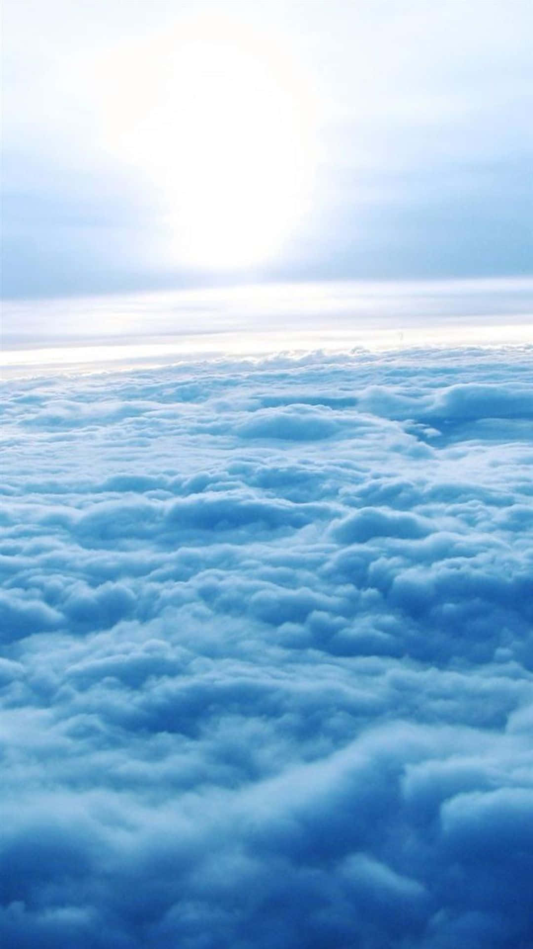 從上方俯瞰蓬鬆的藍色雲層，明亮的太陽