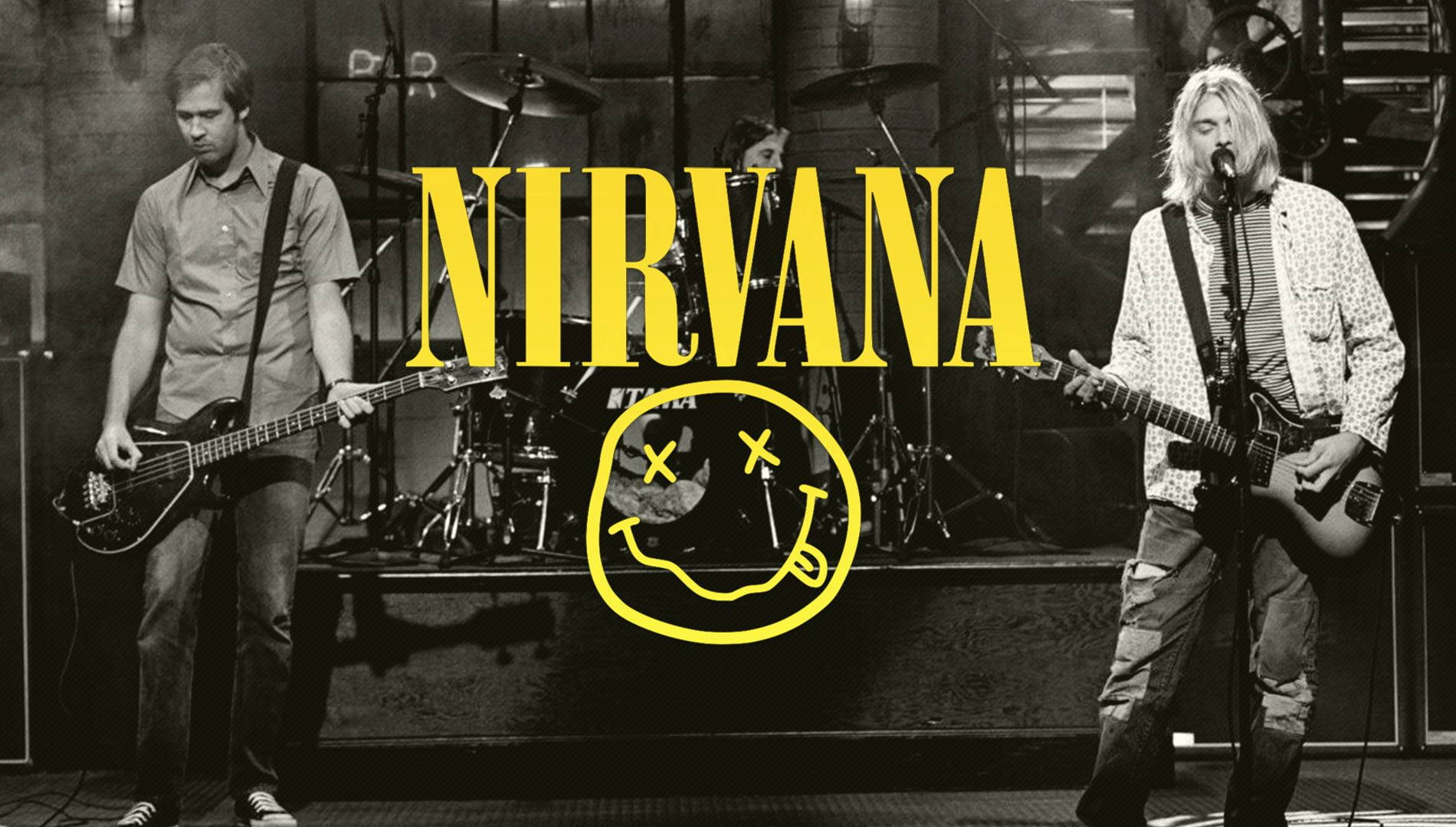 Nirvana 樂隊在舞台上現場表演，帶有黃色笑臉標誌疊加。