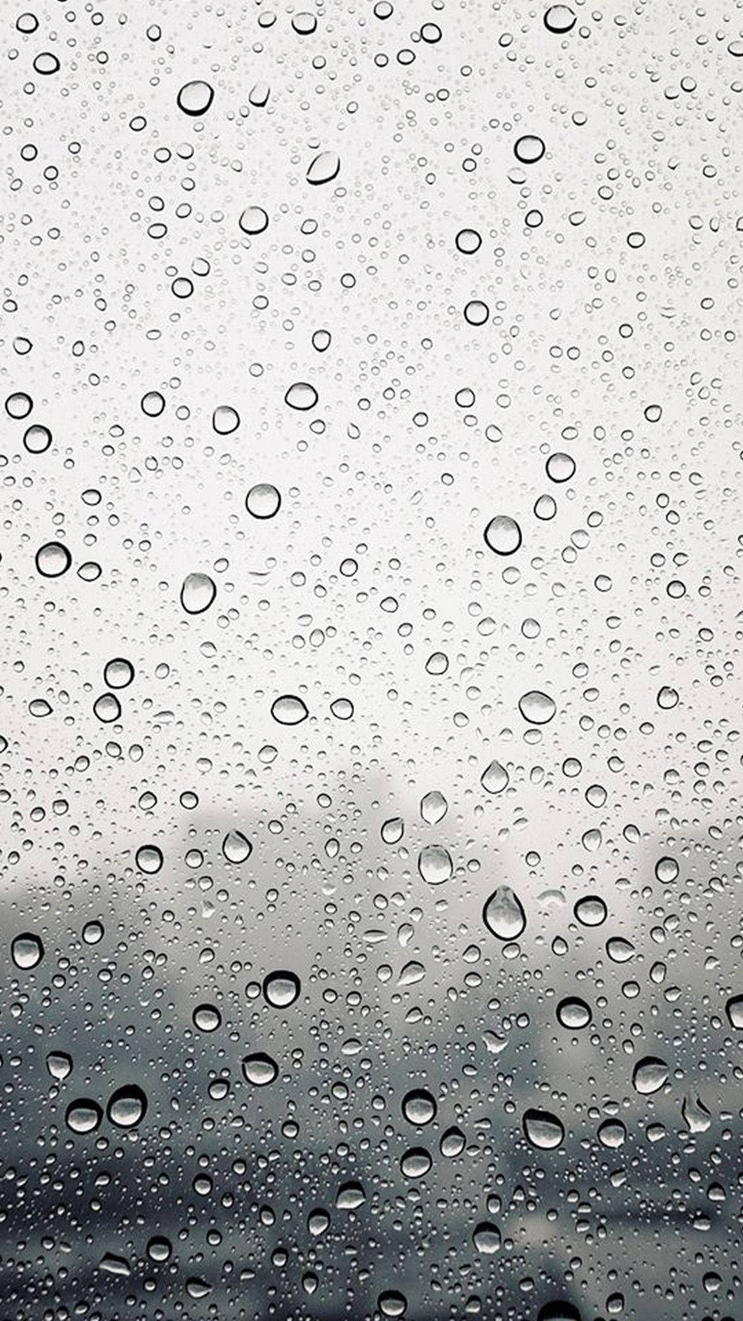 玻璃上的雨滴與模糊的灰色天空背景
