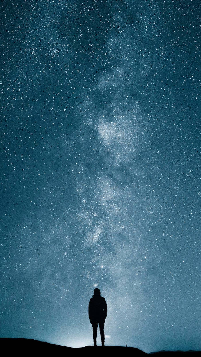 涼爽星系夜空 壁紙 — 一個孤獨的身影站在山頂上，仰望滿是銀河的壯麗星空。