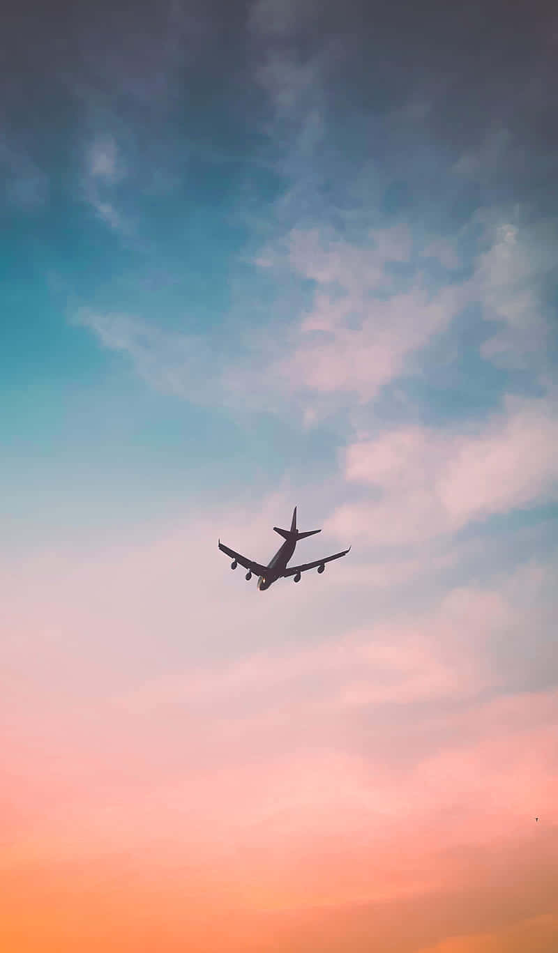 淡彩天空飛行飛機背景肖像 壁紙 — 一架孤獨的飛機在色彩繽紛的暮色天空中呈現剪影，天空塗有柔和的粉紅色、橙色和藍色雲彩。