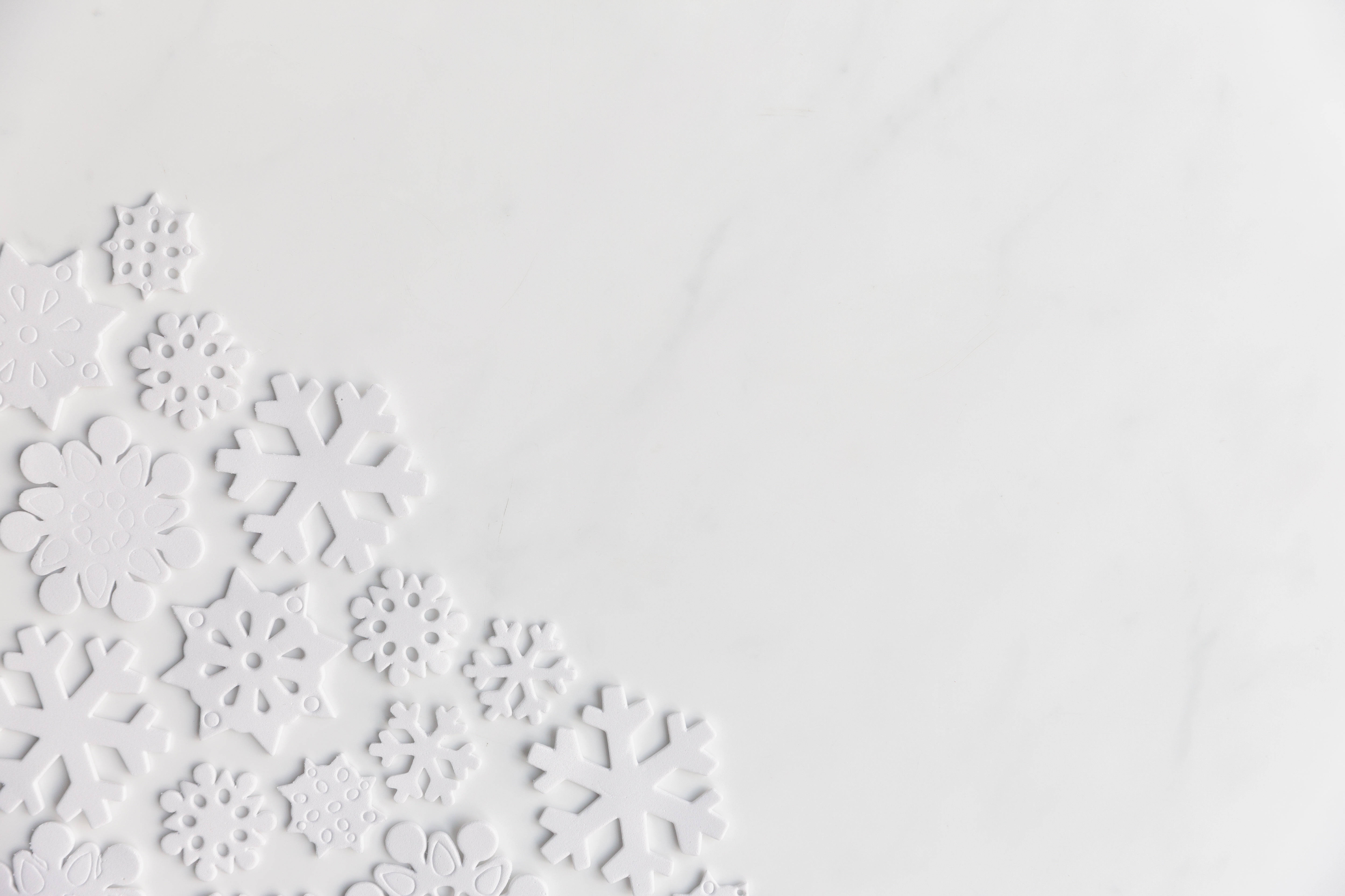 淡雅白色雪花牆 壁紙 — 白色雪花裝飾聚集在光滑白色大理石表面的左下角。