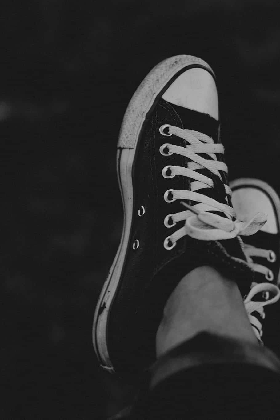 深化你對黑色的理解 壁紙 — 黑色背景上，一雙磨損的Converse運動鞋，白色鞋帶和橡膠鞋底的黑白特寫。