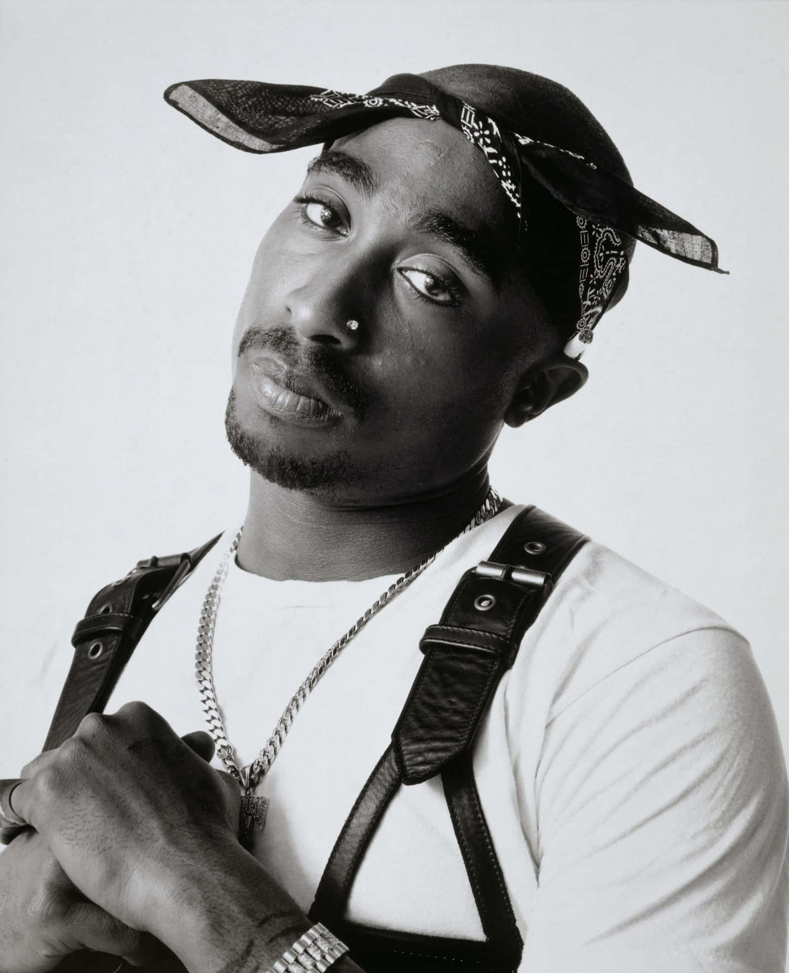 Tupac Shakur 的黑白肖像，戴著頭巾帽和皮革吊帶。