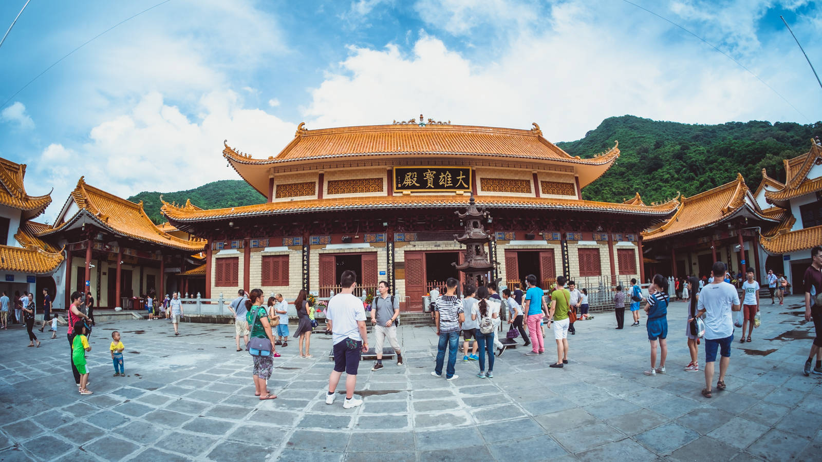 深圳弘法寺 壁紙 — 遊客探索一座宏偉的傳統中式寺廟，擁有金色屋頂和紅色柱子，在明亮的藍天下。