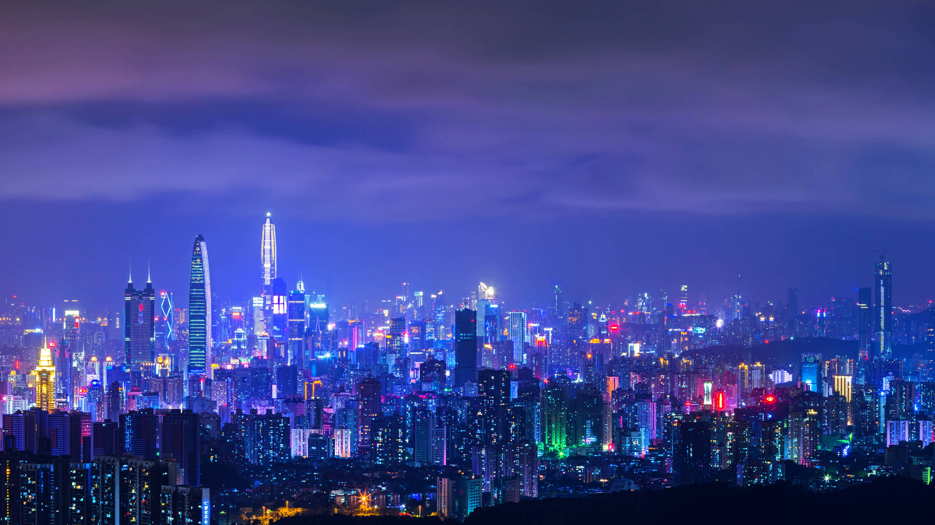 深圳紫夜燈光 壁紙 — 在深紫色天空下，廣闊的城市天際線被鮮豔的霓虹燈照亮。