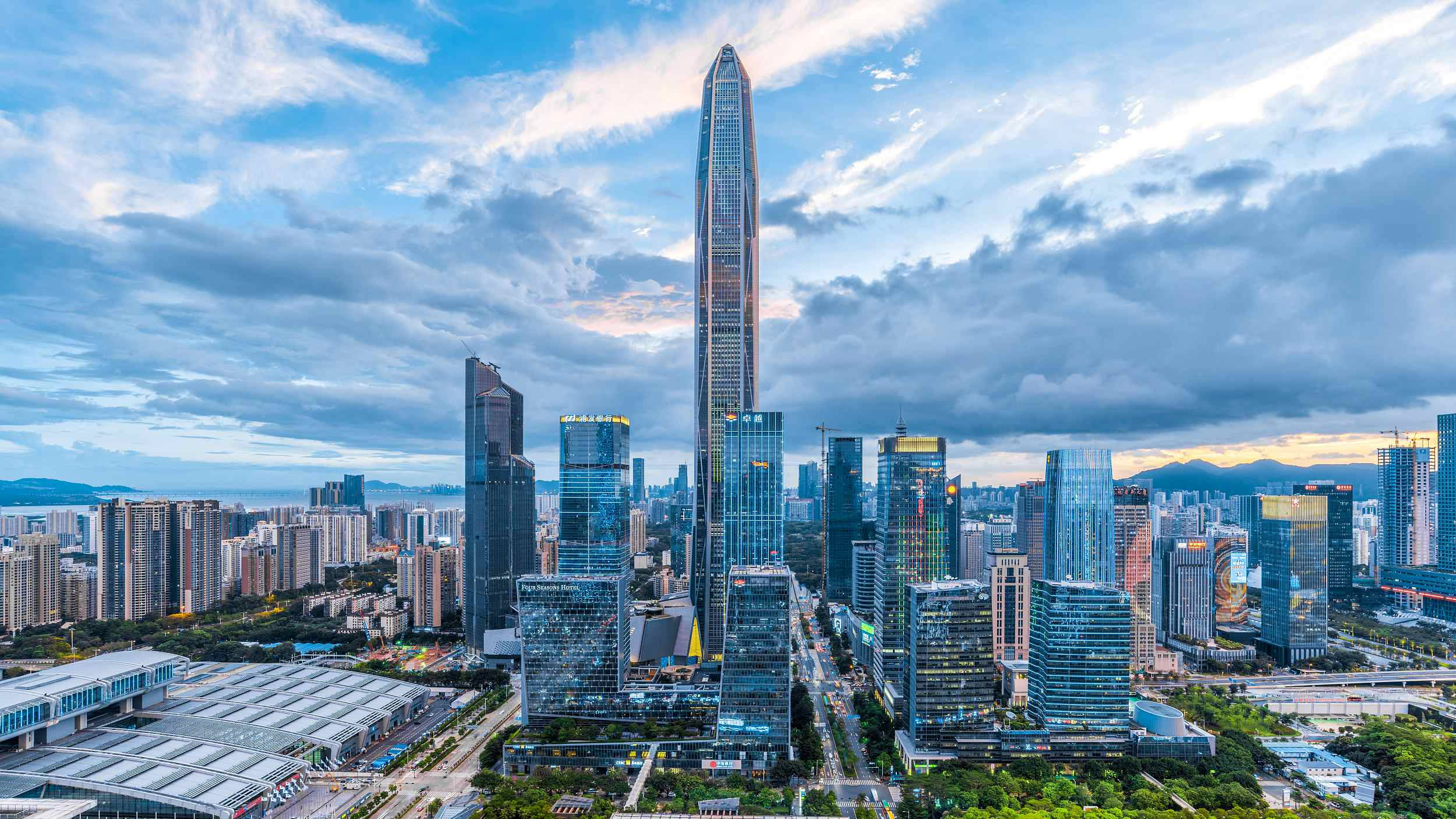 深圳都市風景 壁紙 — 在戲劇性的多雲天空下，由高聳摩天大樓主導的未來城市景觀的鳥瞰圖。