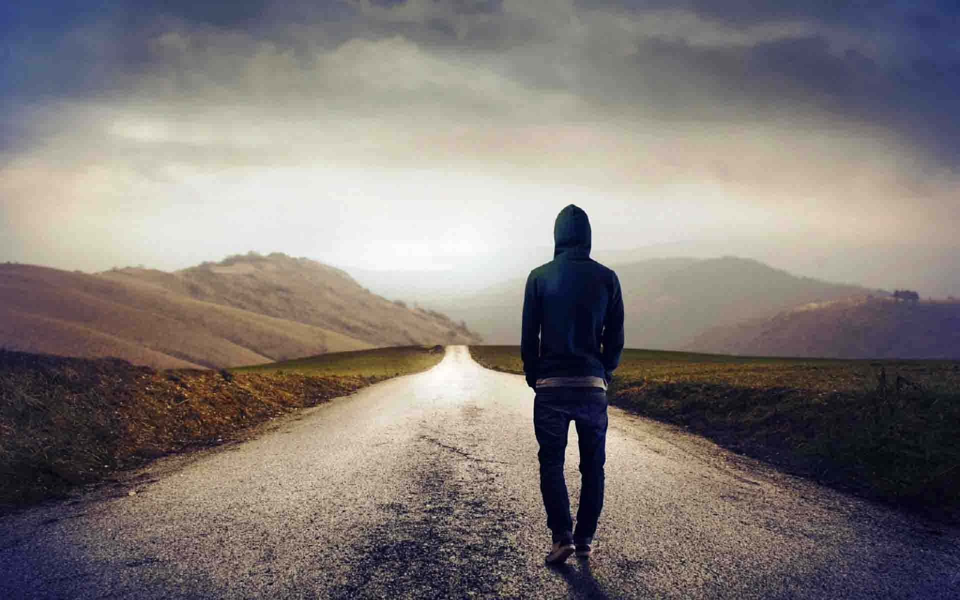 穿連帽衫的人獨自走在黃昏的鄉村道路上