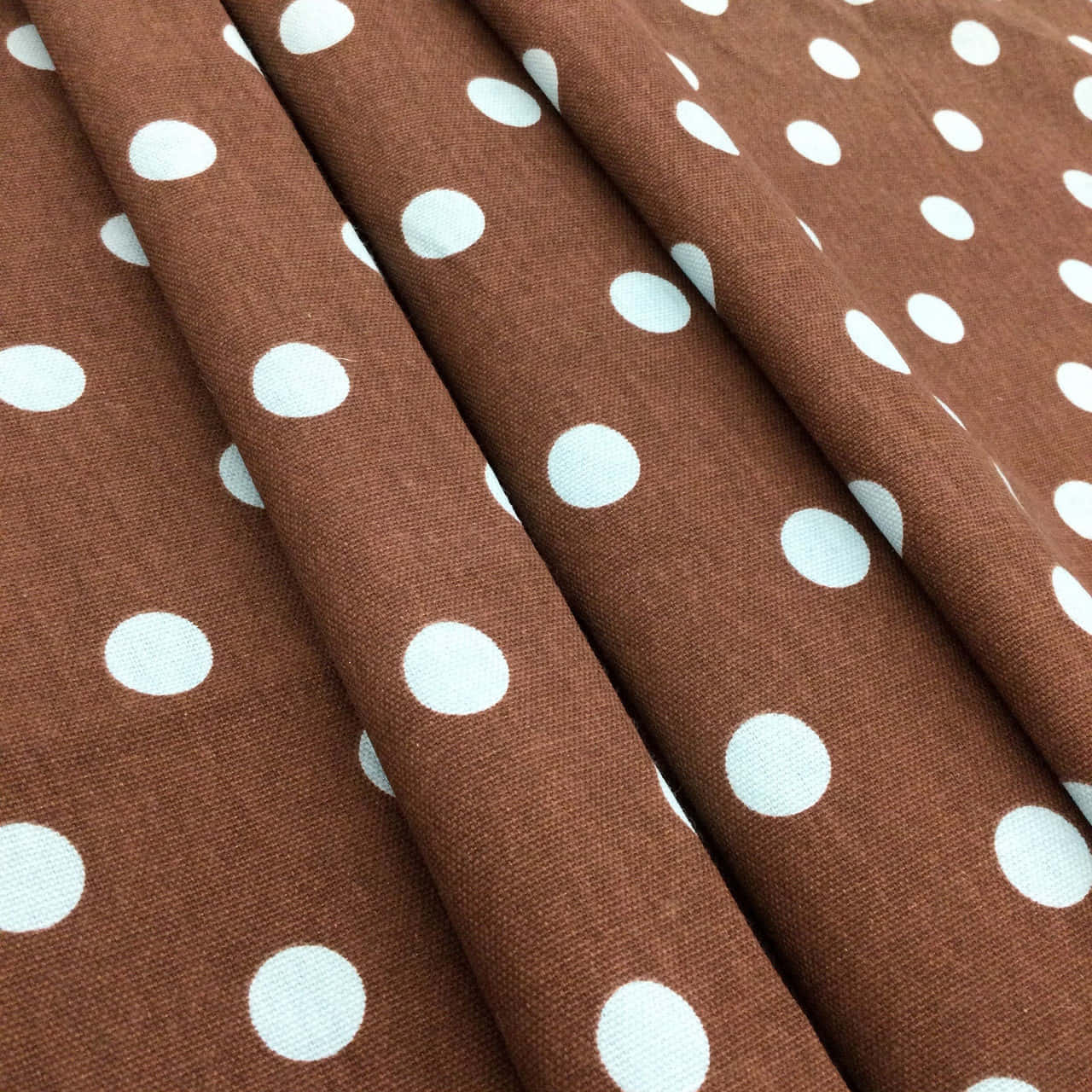 Brown Polka Dots 桌布 壁紙 — 深棕色布料上帶有白色圓點，以柔軟的對角皺褶折疊的特寫。