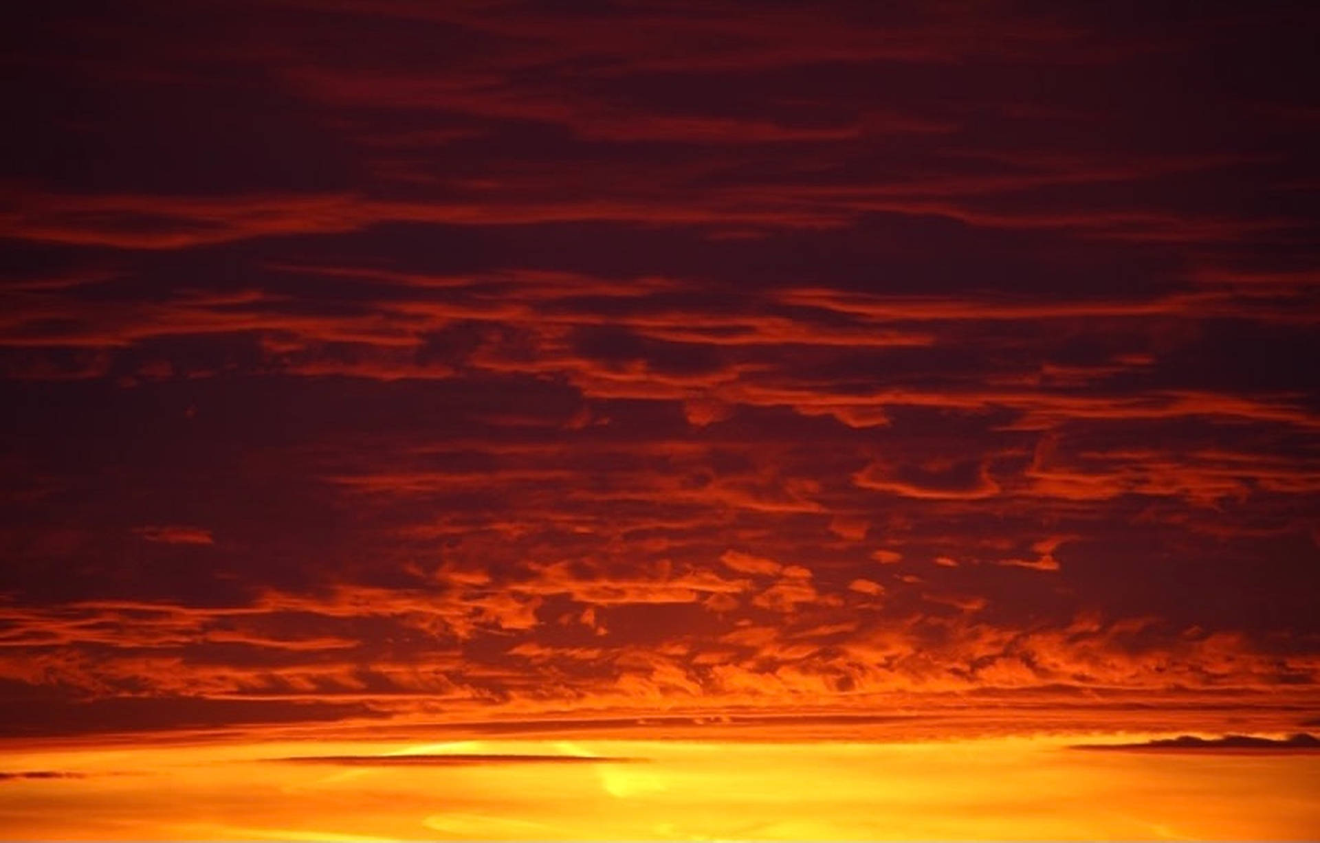 熾熱的紅色和橙色夕陽雲朵在金色地平線上方發光。
