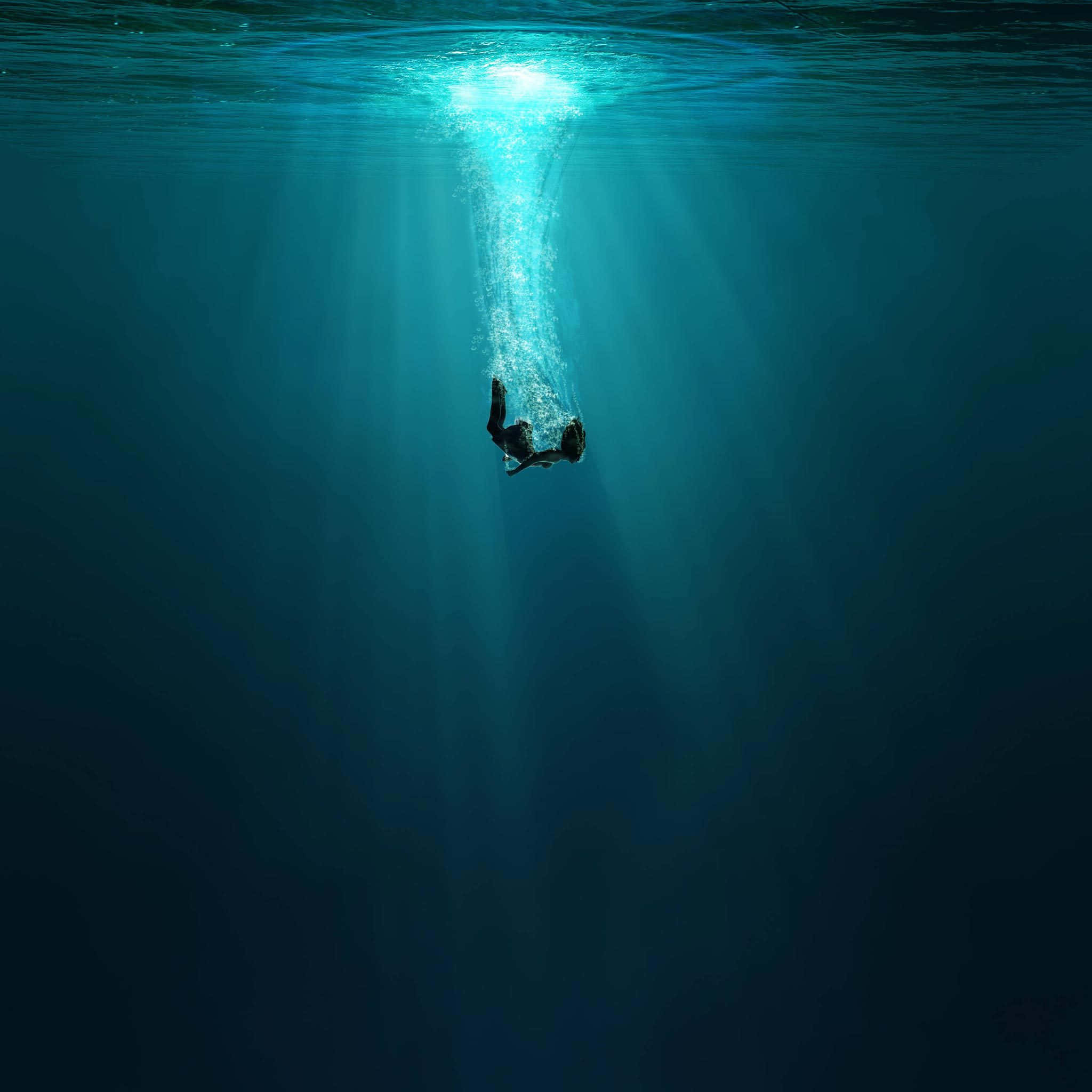 深海的奧秘 壁紙 — 一名潛水員潛入深藍色的海洋，陽光從上方照射下來，形成一條發光的氣泡軌跡。