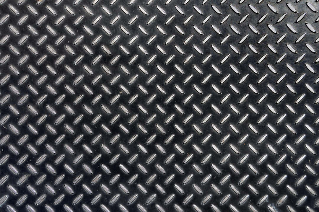 Diamond Plate 桌布 壁紙 — 深灰色菱形花紋金屬表面的特寫，帶有凸起的菱形圖案和細微反射。