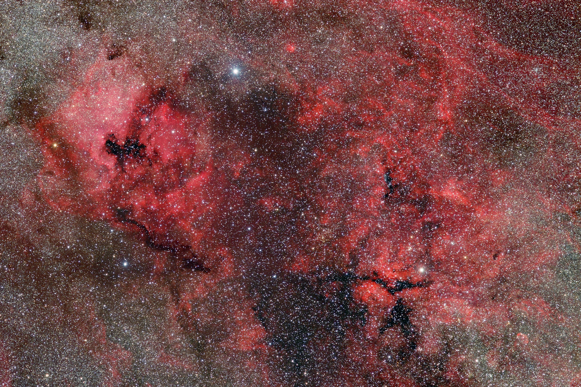 一個充滿星星和黑暗宇宙塵埃雲的鮮豔紅色星雲。