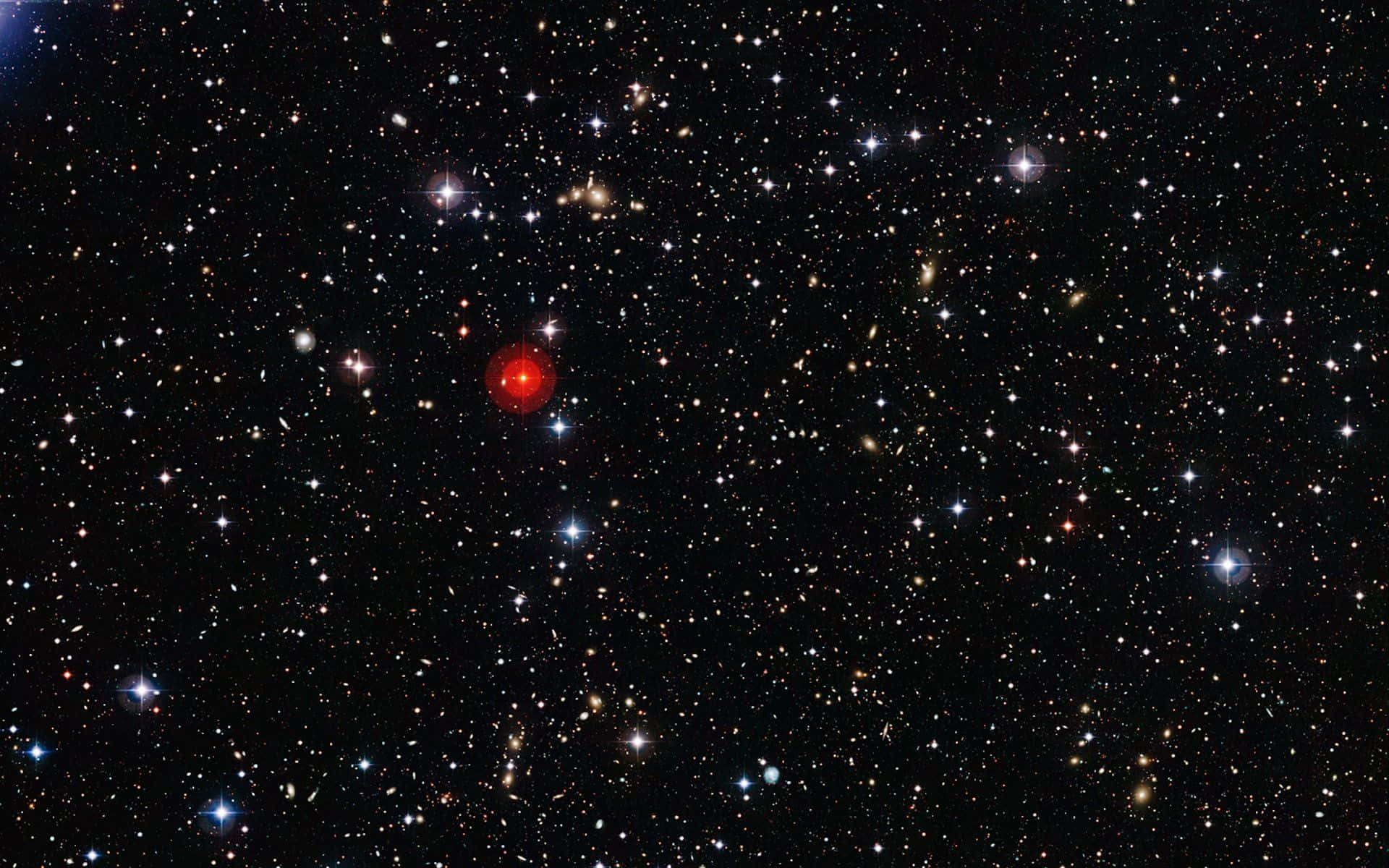 深空紅色恆星圖像 壁紙 — 一個充滿無數恆星和星系的深空視圖，以一顆明亮的紅色恆星在黑色虛空中閃耀為特色。
