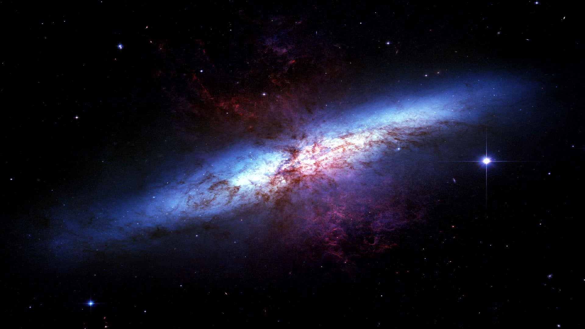 深空虛無圖像 壁紙 — 一個令人驚嘆的螺旋星系，在佈滿星辰的宇宙虛空中閃耀著藍色和紅色的星雲。