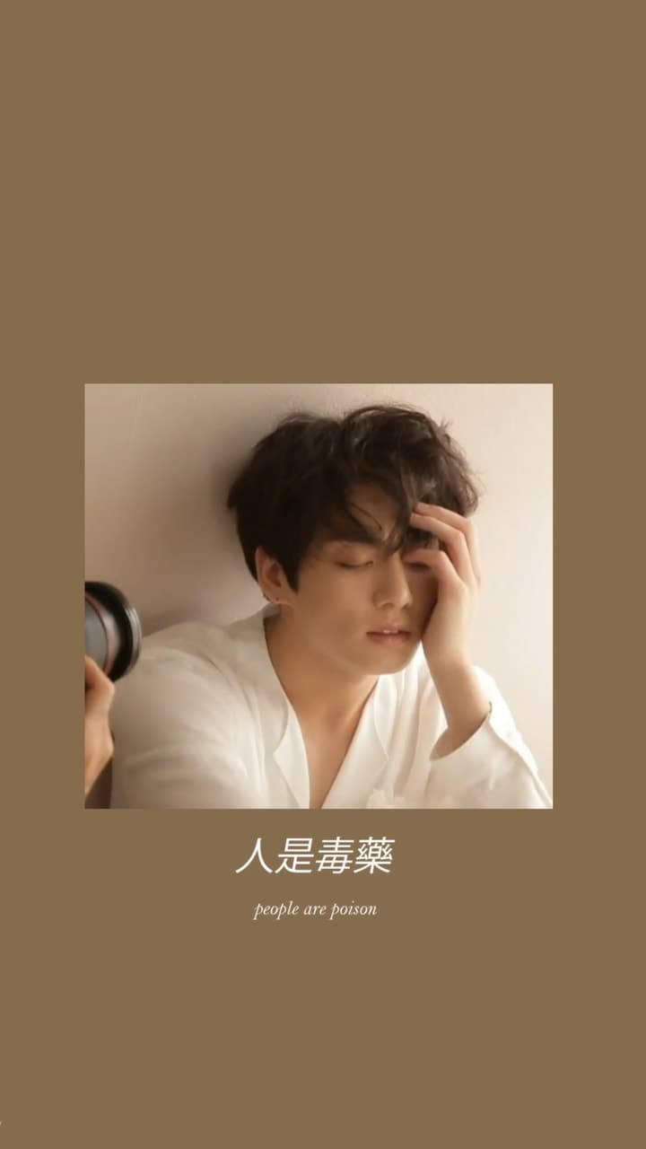 深米色 Jungkook 美學壁紙 壁紙 — 一位身穿白恤衫的年輕男子將頭靠在牆上，一手放在額前，手持一個小鏡子，傳達出安靜的內省。