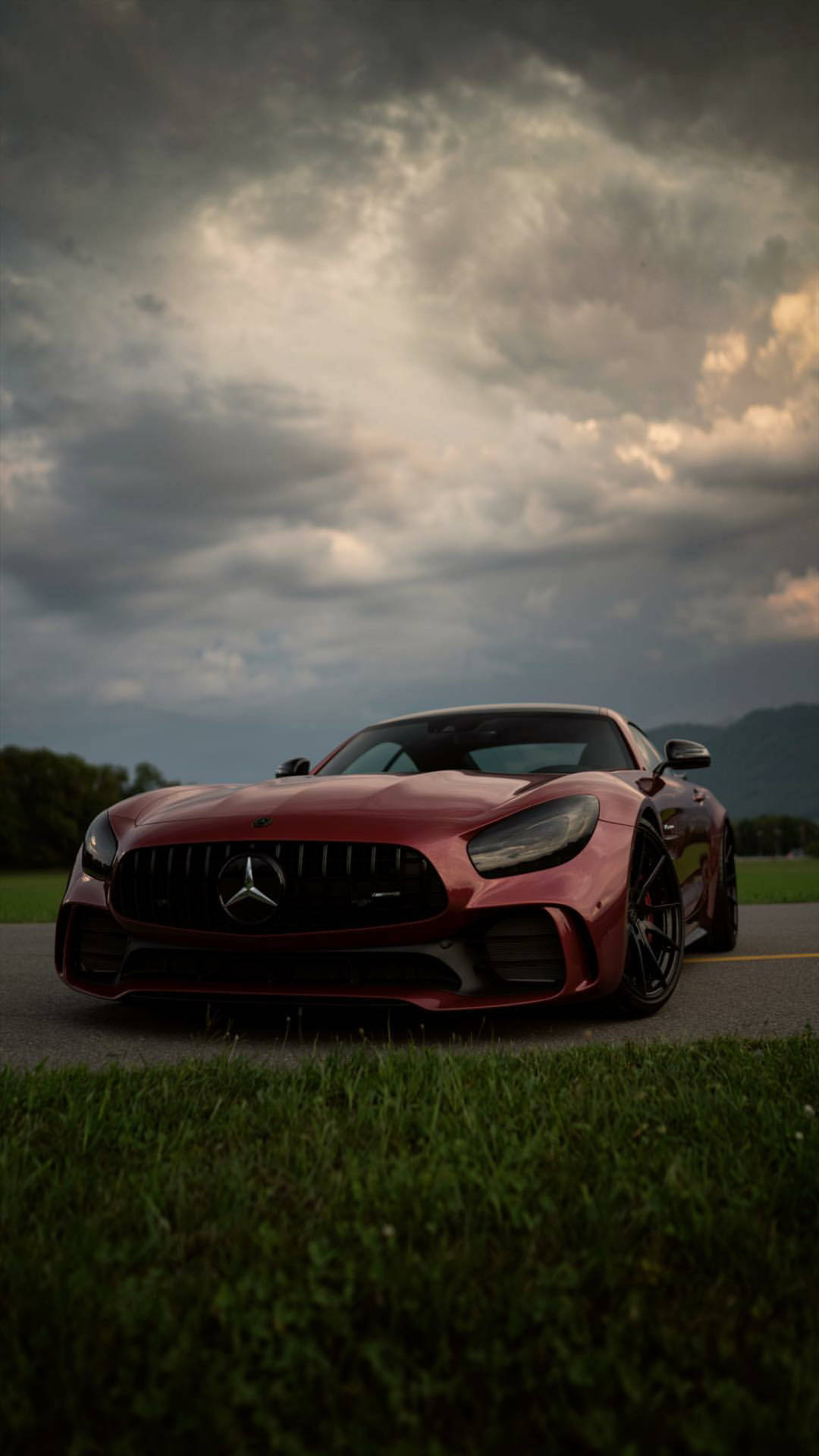 紅色 Mercedes-AMG GT 跑車停泊在路邊，天空風起雲湧。