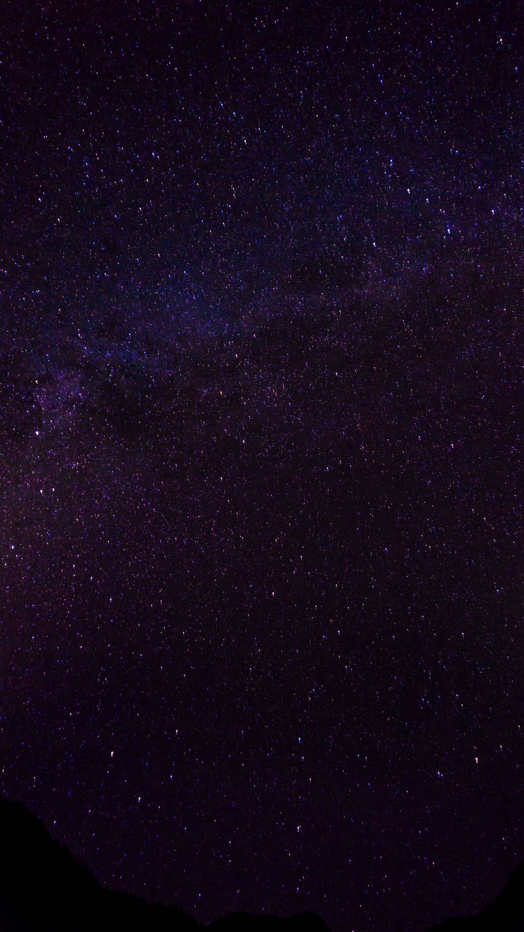 夜晚，黑暗山巒輪廓上方，銀河系呈現紫色和藍色星星。
