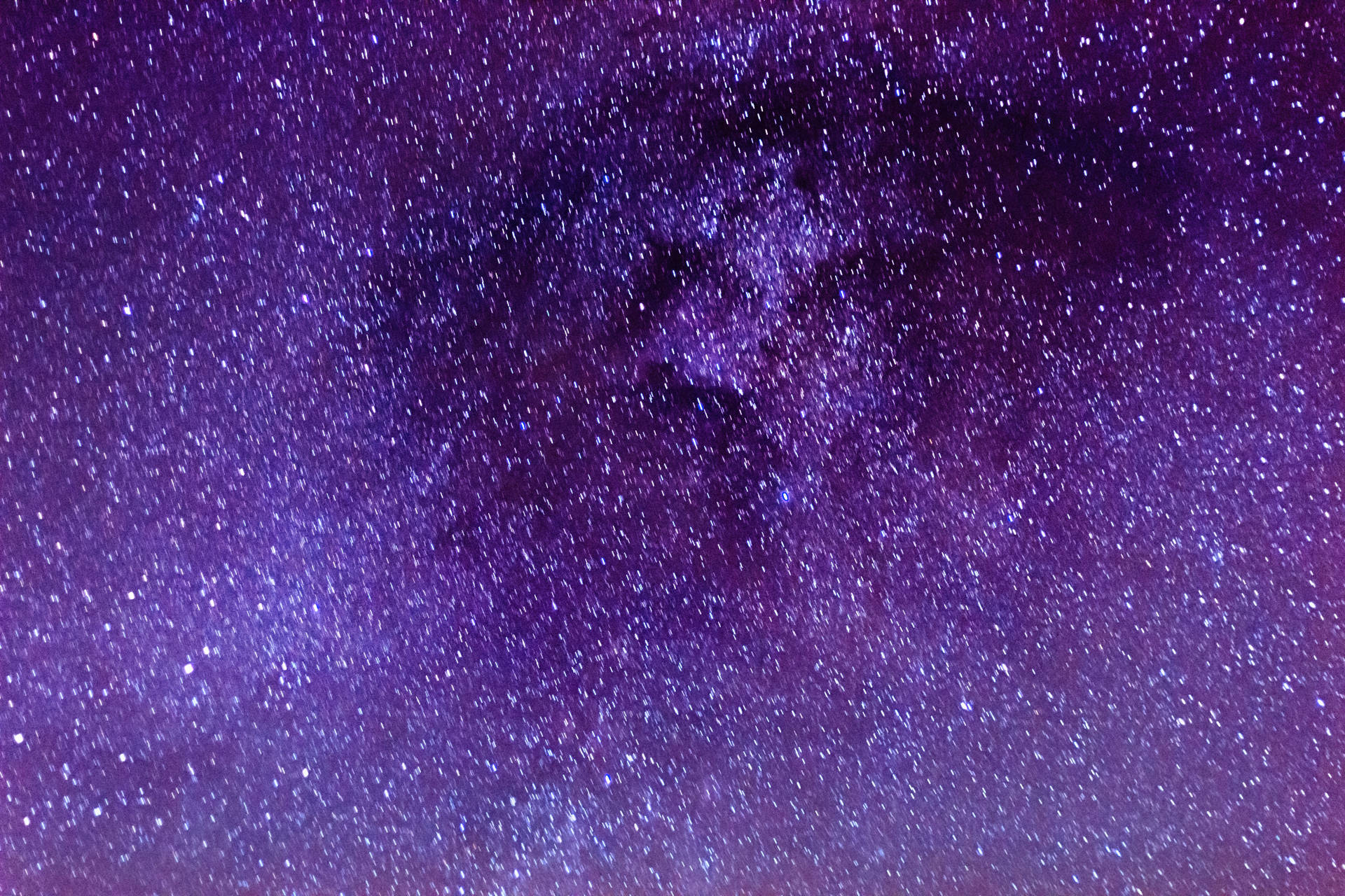 夜空中廣闊的紫色和藍色星場，帶有發光的宇宙塵埃雲。