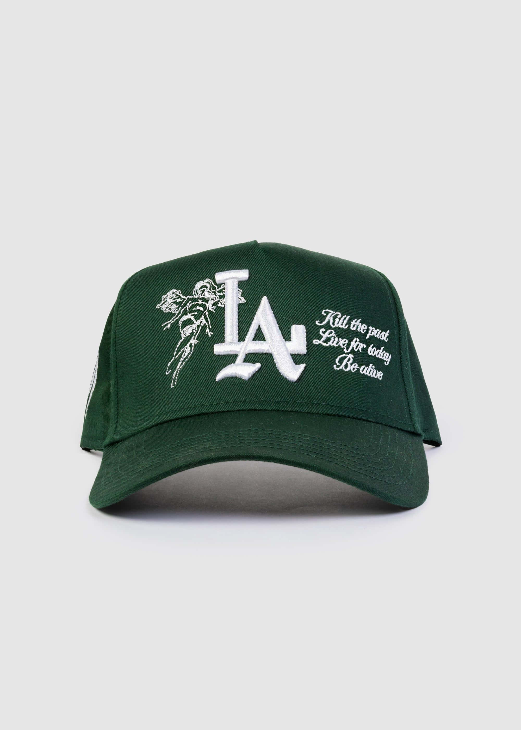 Hat 桌布 壁紙 — 深綠色棒球帽，帶有白色刺繡LA標誌、天使圖案和勵志語句，背景簡潔。